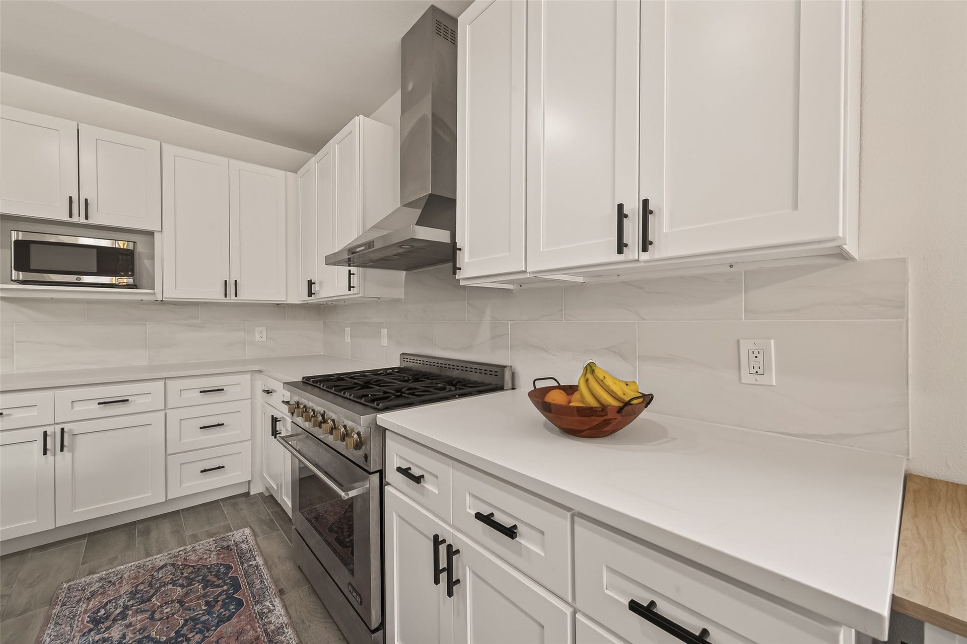 4423 Parkwater Cove Court SE, Sugar Land, TX 77479 Modern kitchen with sleek white cabinetry and black hardware. Features a stainless steel gas range with a hood and ample counter space. The light tile backsplash complements the clean design.
