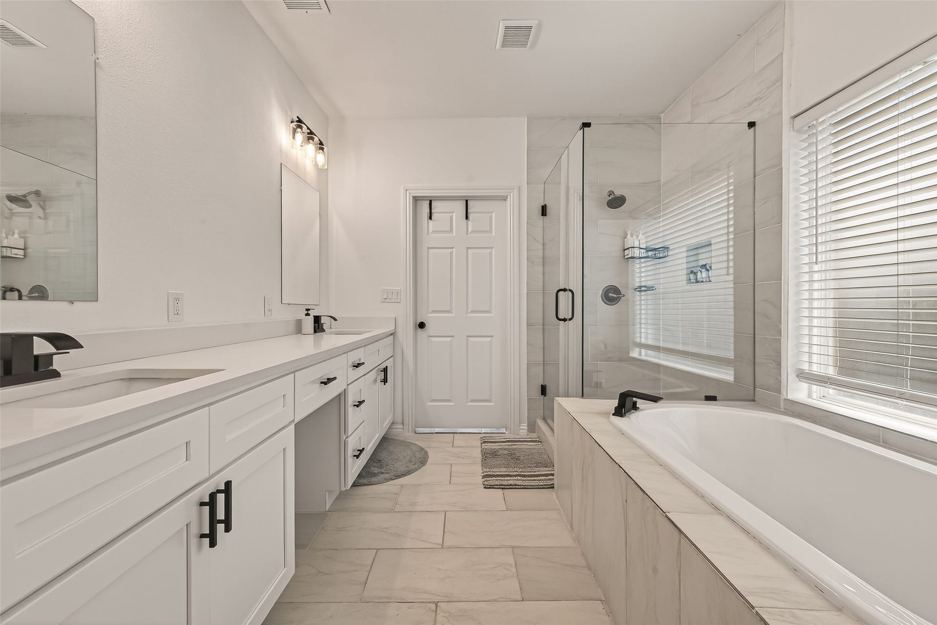 4423 Parkwater Cove Court SE, Sugar Land, TX 77479 This modern bathroom features a spacious layout with a double vanity, sleek fixtures, a large glass-enclosed shower, and a luxurious soaking tub surrounded by natural light from the window.