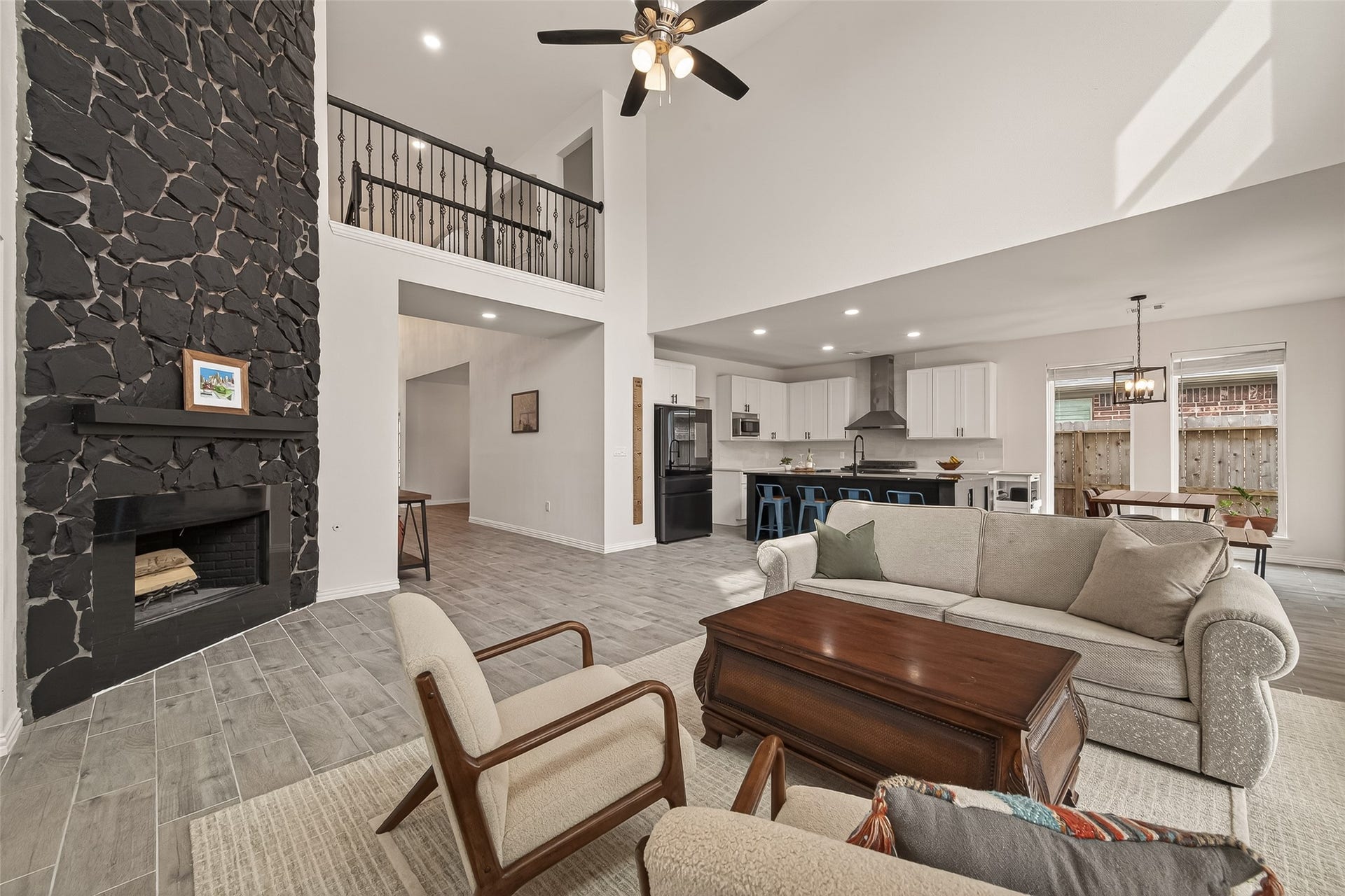 4423 Parkwater Cove Court SE, Sugar Land, TX 77479 This spacious open-concept living area features high ceilings and a striking stone fireplace, perfect for cozy gatherings. The updated modern kitchen boasts sleek cabinetry, a large island with bar seating, and a dining area with natural light. Ideal for entertaining and family living.