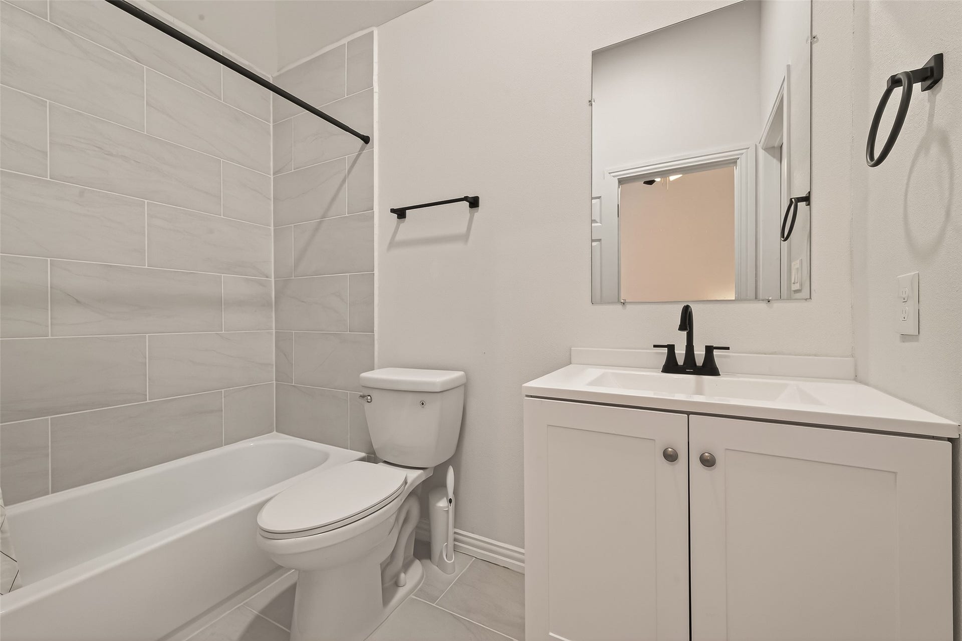 4423 Parkwater Cove Court SE, Sugar Land, TX 77479 This bathroom features a modern design with a sleek vanity, black fixtures, and a large mirror. It includes a bathtub with a stylish tiled shower surround, offering a clean and contemporary look.