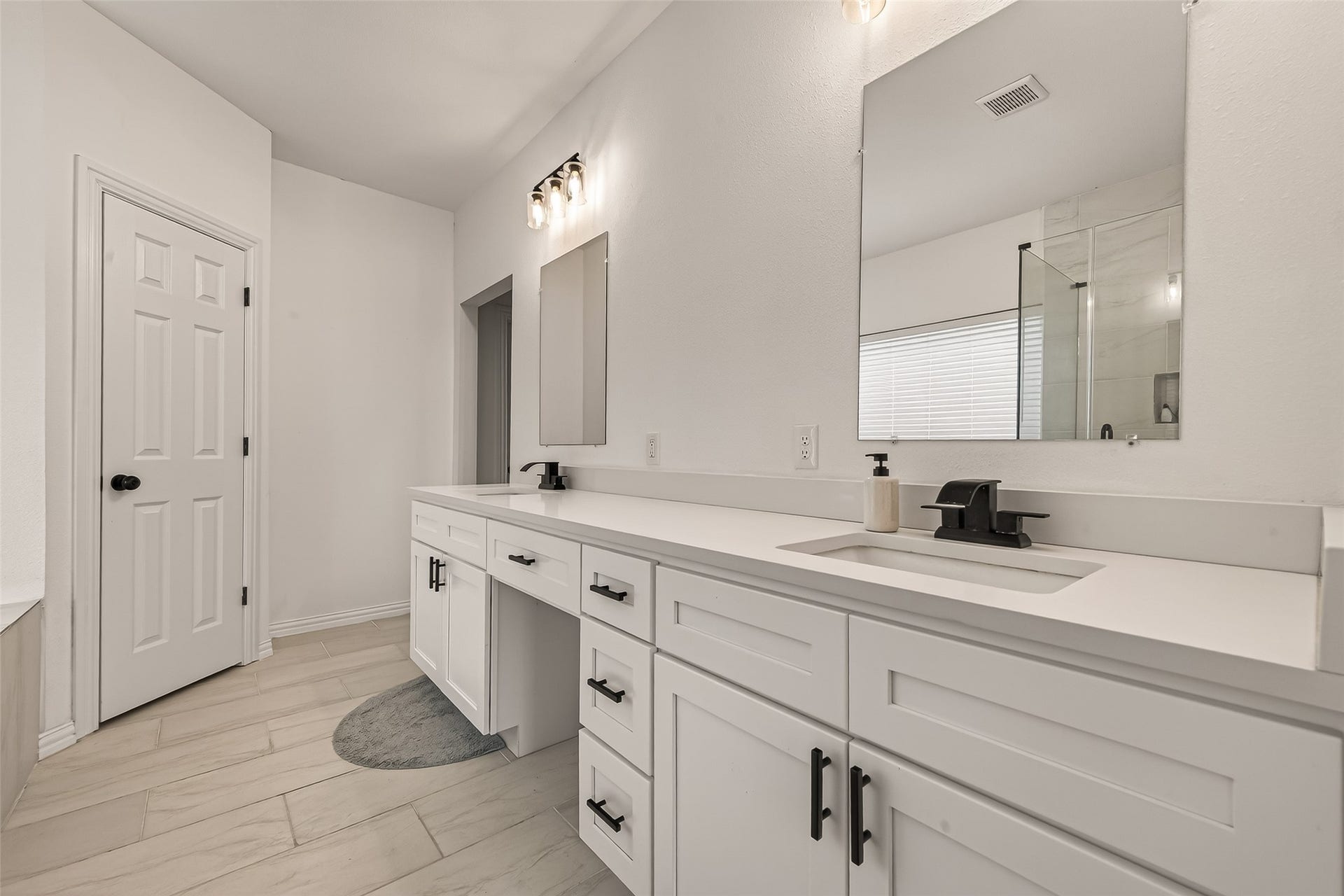 4423 Parkwater Cove Court SE, Sugar Land, TX 77479 This bathroom features a modern design with a dual-sink vanity, sleek black fixtures, and a large mirror. The room is bright and spacious, with neutral tones and a tiled floor, creating a clean and elegant atmosphere.