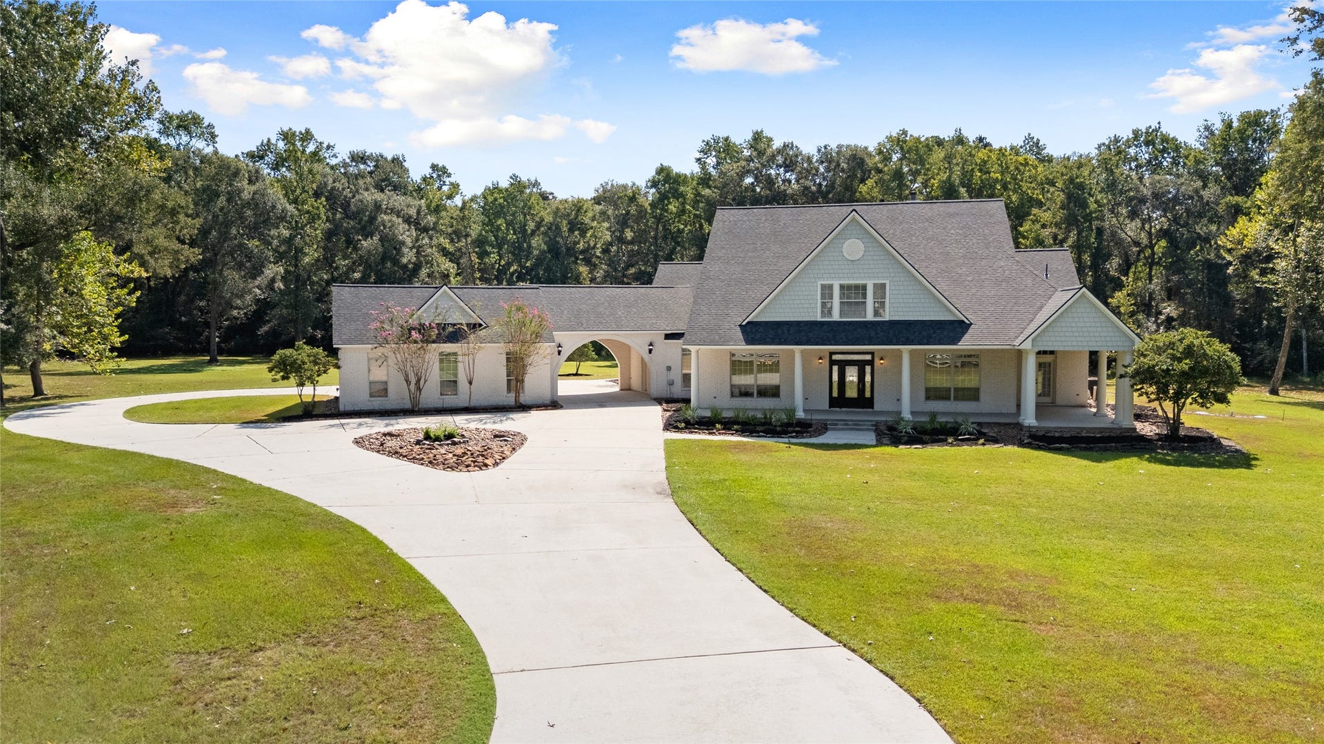 28930 Reserve Bend Drive, Huffman, TX 77336 Impressive exterior showcases the sweeping circular driveway, porte-cochre, covered front porch, and private wooded setting.