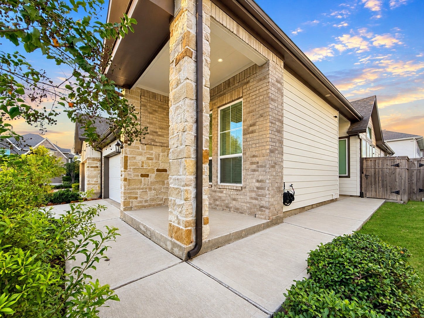 9407 Lantern Light Drive, Missouri City, TX 77459 Covered porch. Showcasing the exterior view showcasing the stone accents, covered entry, and beautifully landscaped walkway.
