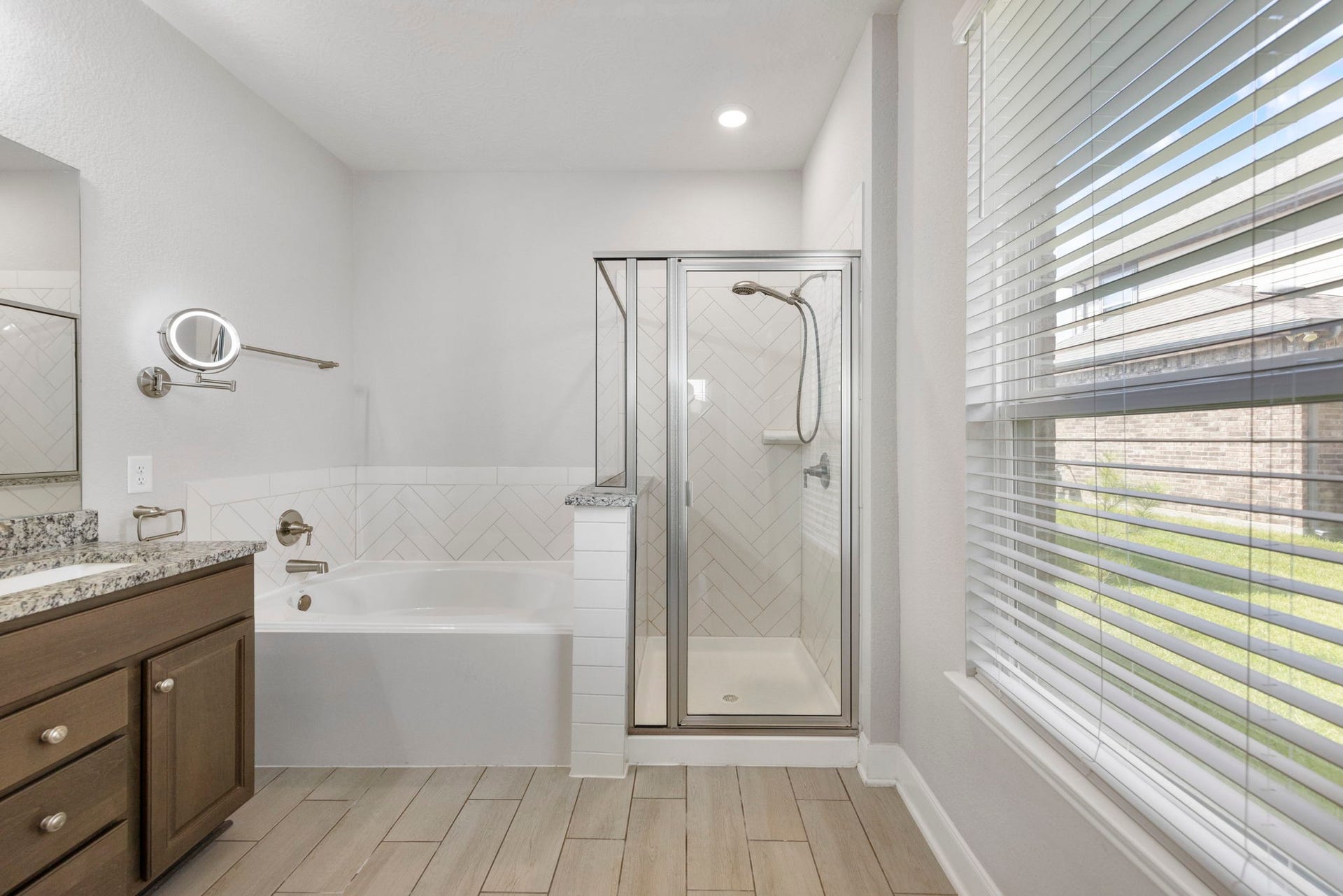 8731 Ute Creek Lane, Magnolia, TX 77354 Relaxing primary bathroom with separate tub & shower featuring herringbone tile work.