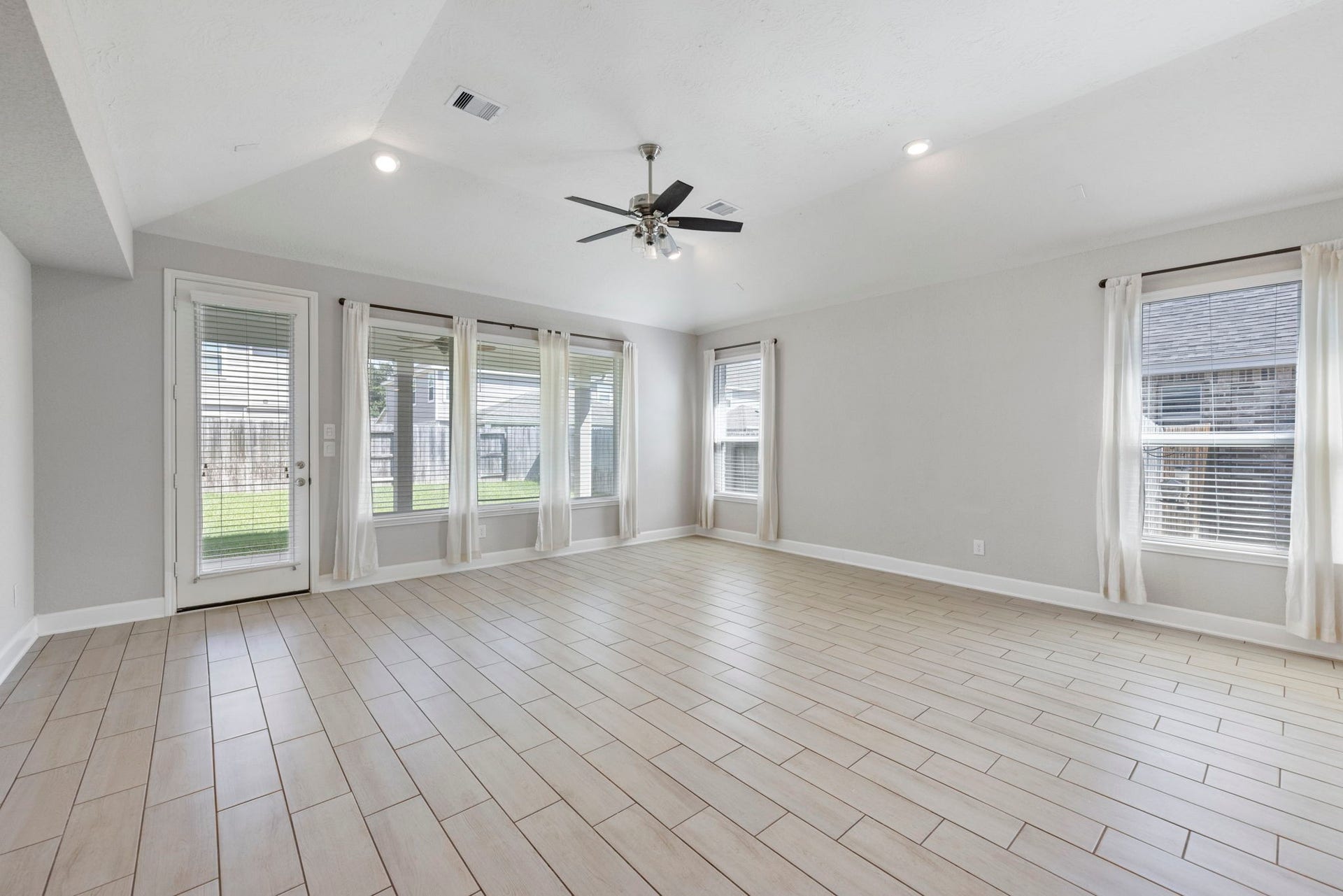 8731 Ute Creek Lane, Magnolia, TX 77354 amily room with high ceilings, ceiling fan, and backyard views.