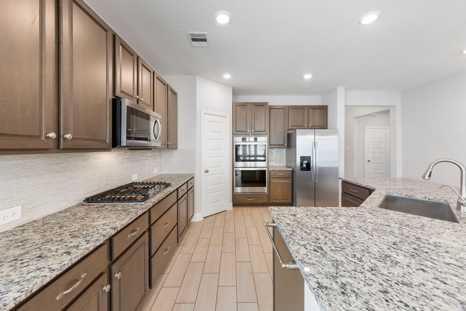 8731 Ute Creek Lane, Magnolia, TX 77354 Stainless double wall oven, gas cooktop, side-by-side refrigerator, and walk-in pantry