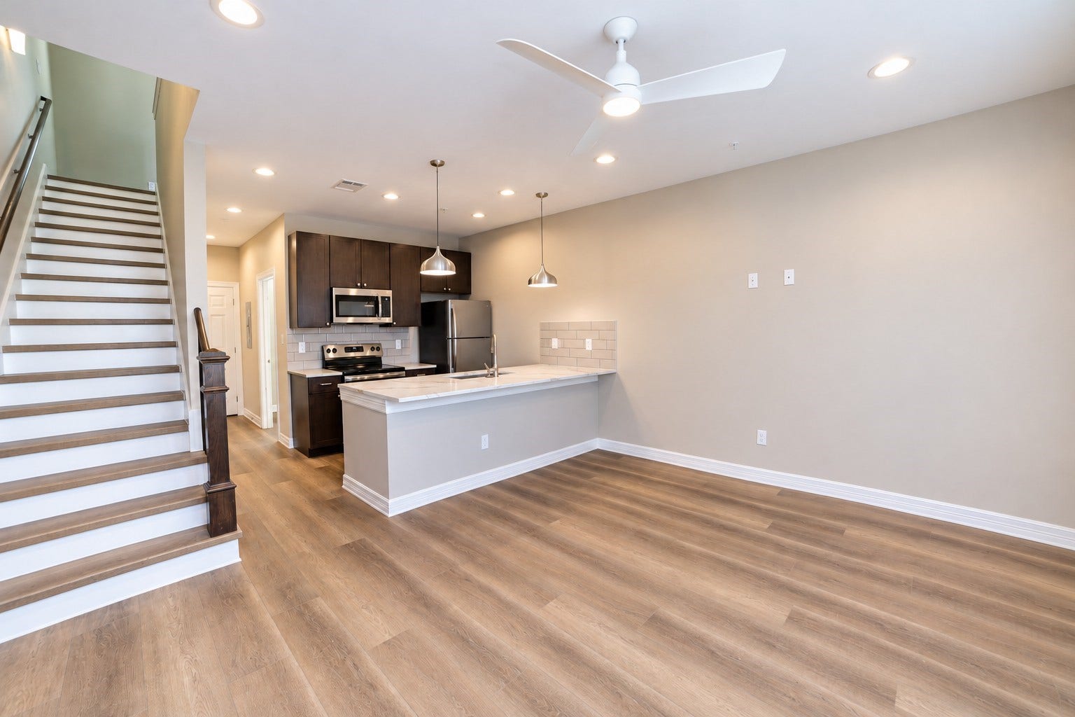 3252 Creekmont Drive, Houston, TX 77091 Modern open-concept living area featuring sleek vinyl floors, a stylish kitchen with stainless steel appliances, and a spacious countertop, complemented by contemporary lighting and a ceiling fan.