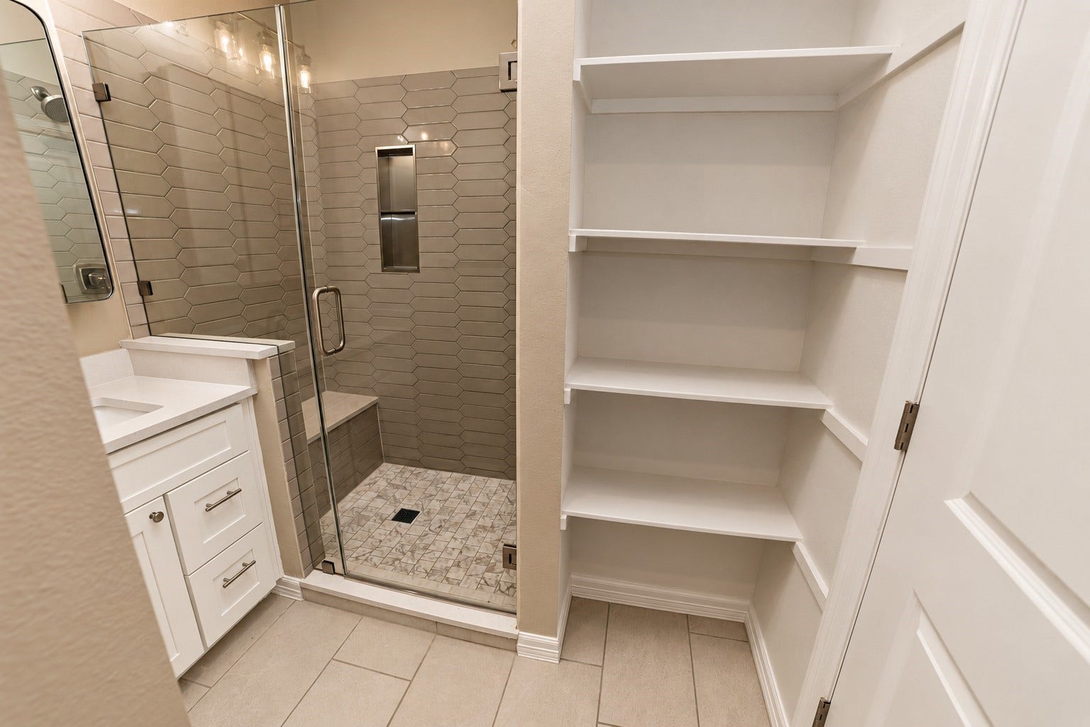 3252 Creekmont Drive, Houston, TX 77091 Elegant bathroom featuring a glass-enclosed shower with modern tilework, a sleek vanity, in shower bench and built-in shelving for ample storage.