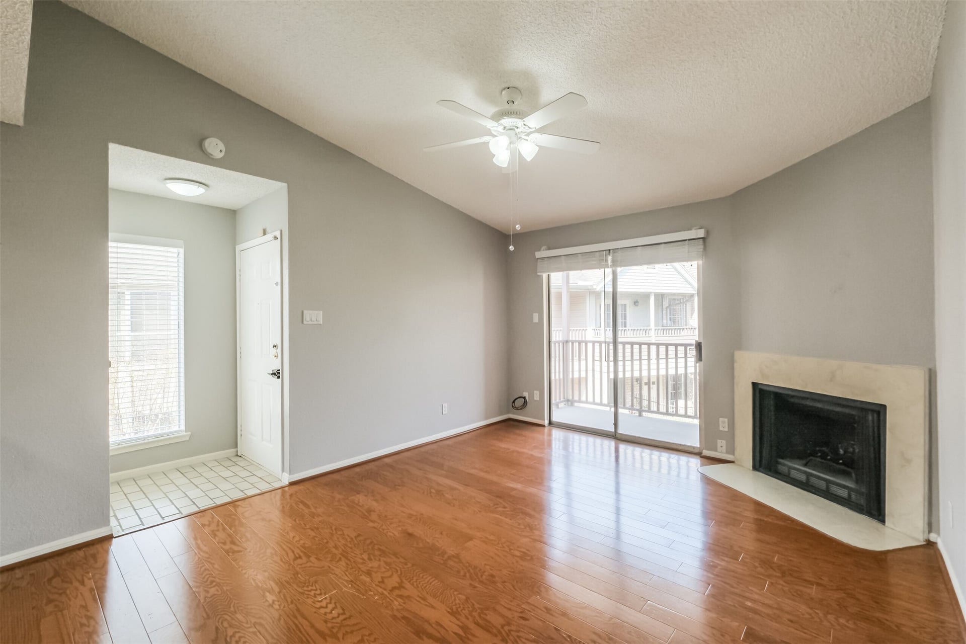 3100 Jeanetta Street, #1204, Houston, TX 77063 Inviting living room filled with natural light from large windows, complemented by hardwood floors and a cozy fireplace!
