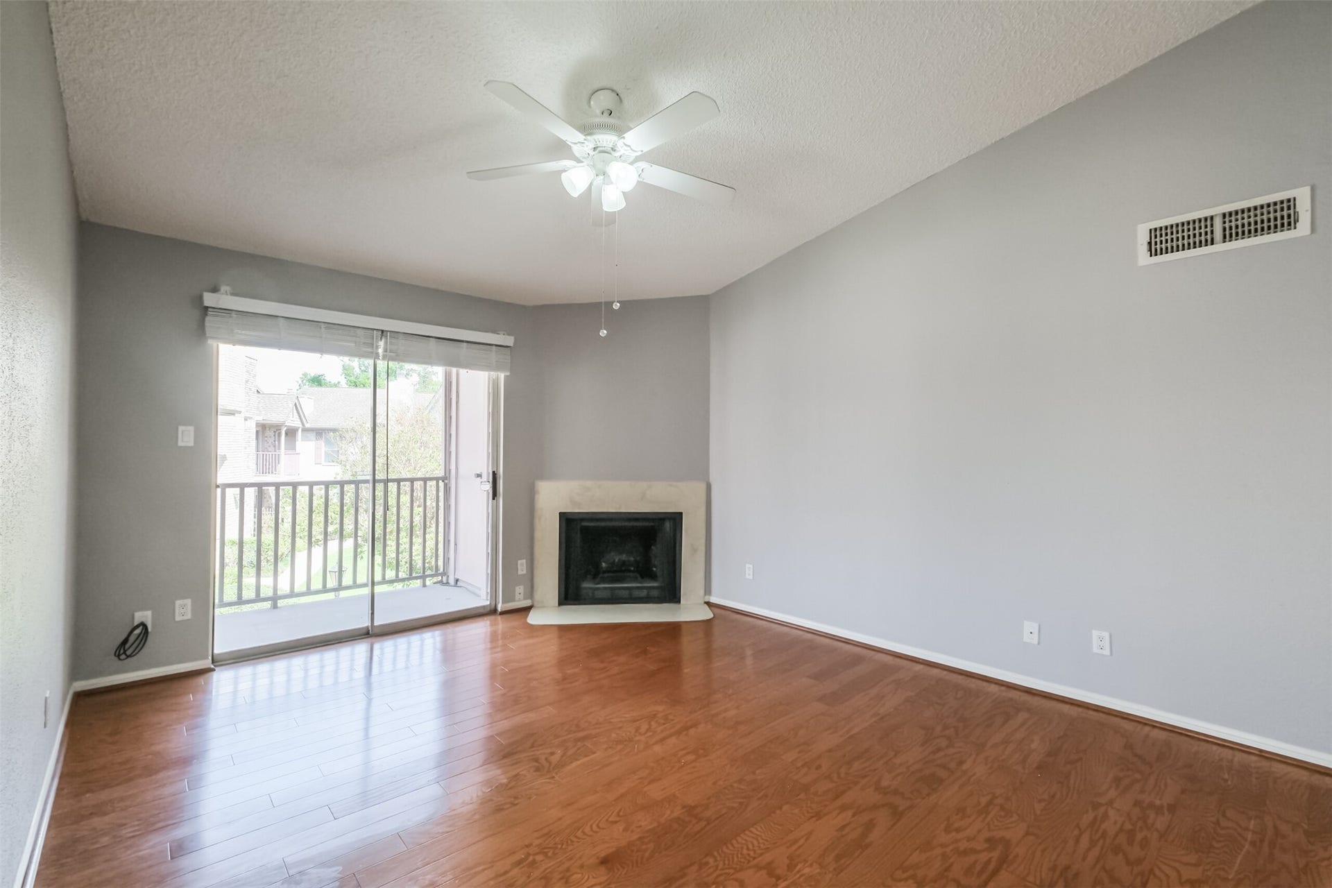 3100 Jeanetta Street, #1204, Houston, TX 77063 Inviting living room filled with natural light from large windows, complemented by hardwood floors and a cozy fireplace!