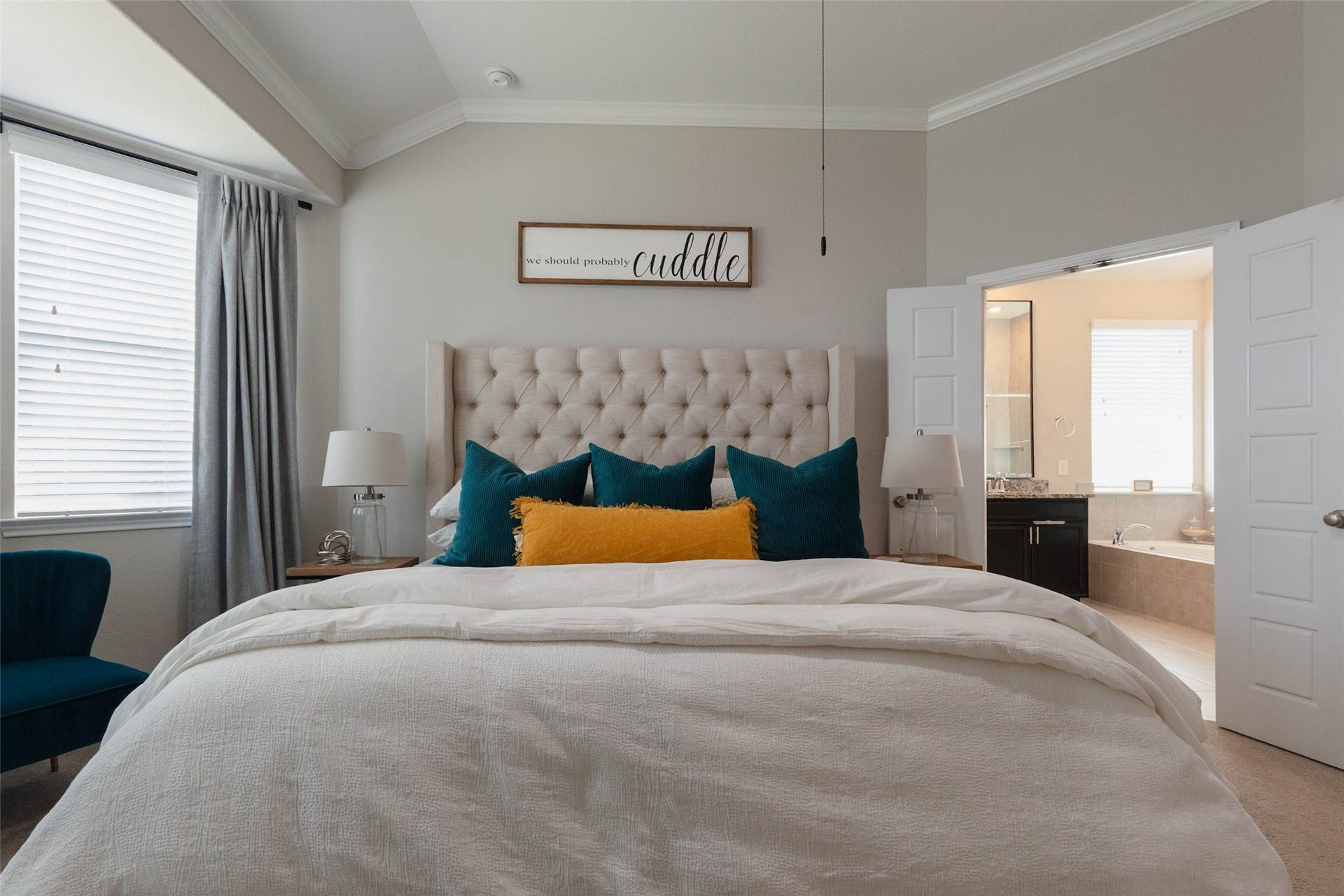 Spacious primary bedroom featuring a tray ceiling, neutral finishes, and natural light.