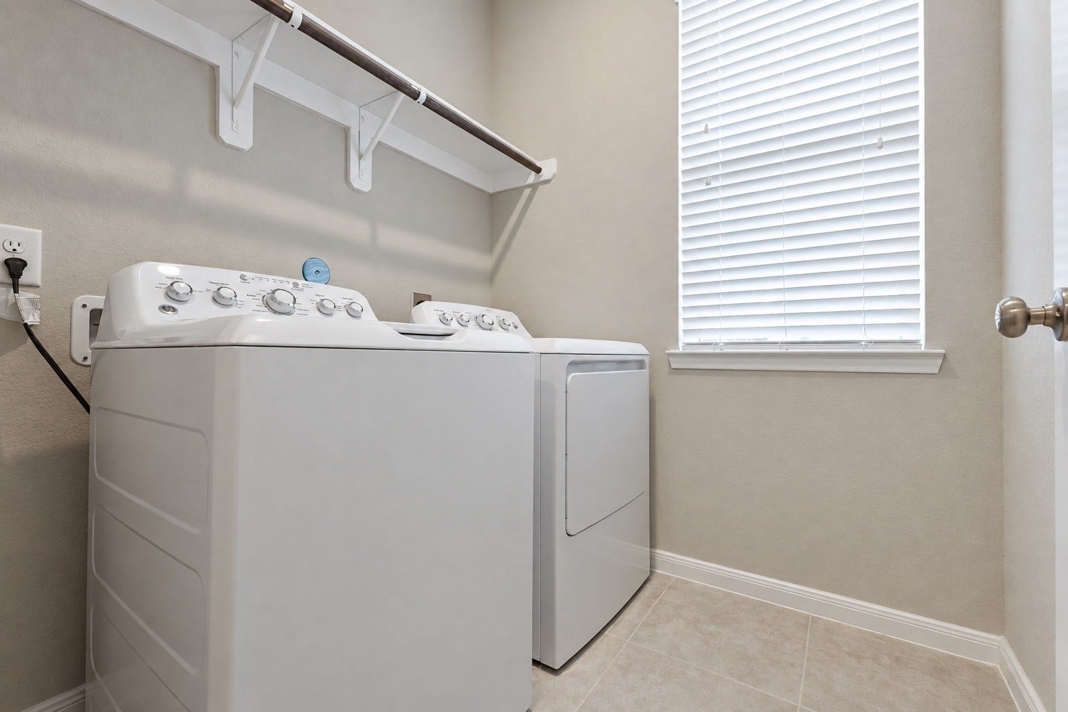Dedicated laundry room featuring built-in shelving, washer and dryer hookups, and additional storage space.