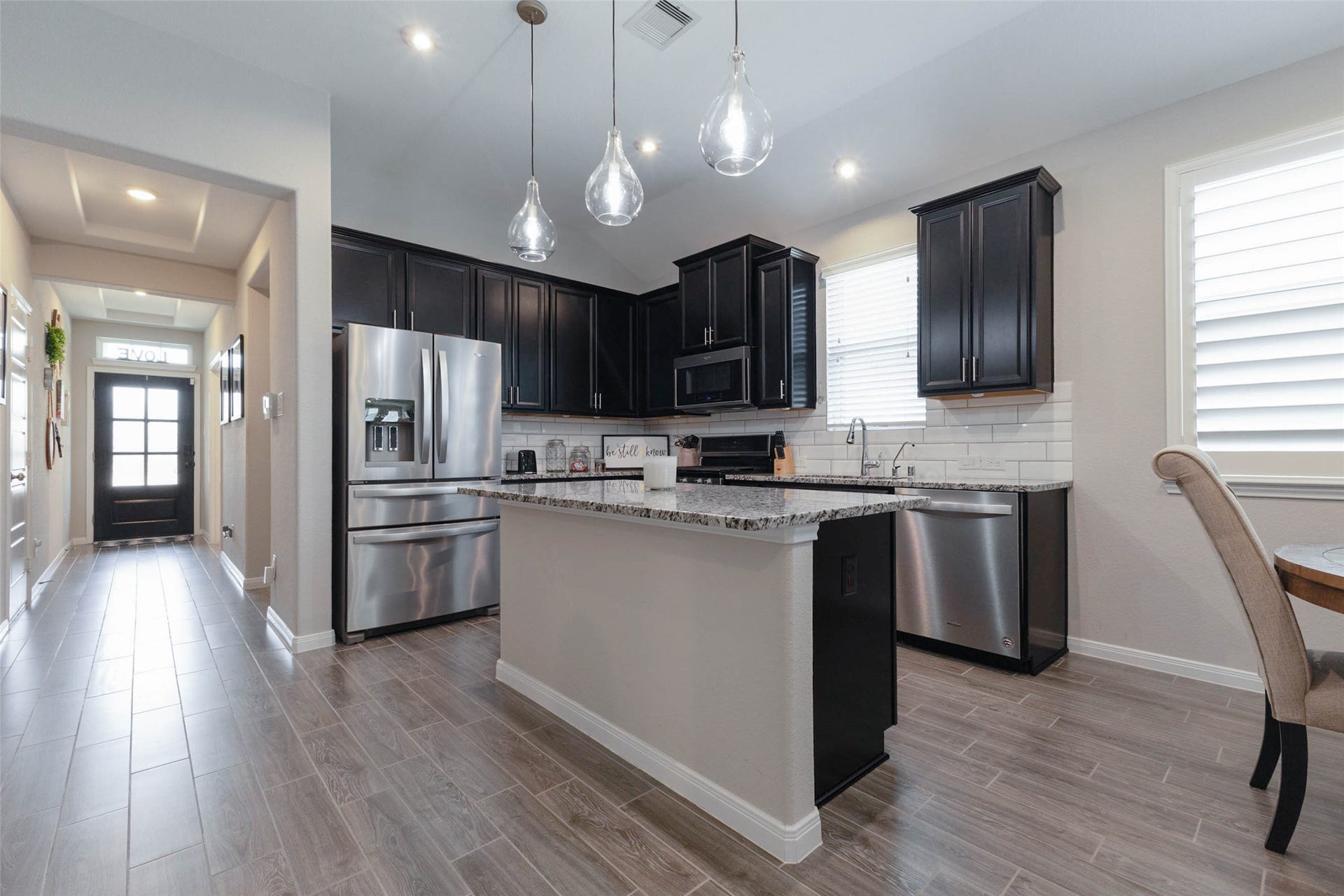 Open-concept kitchen featuring dark cabinetry, a center island, stainless steel appliances, and pendant lighting.