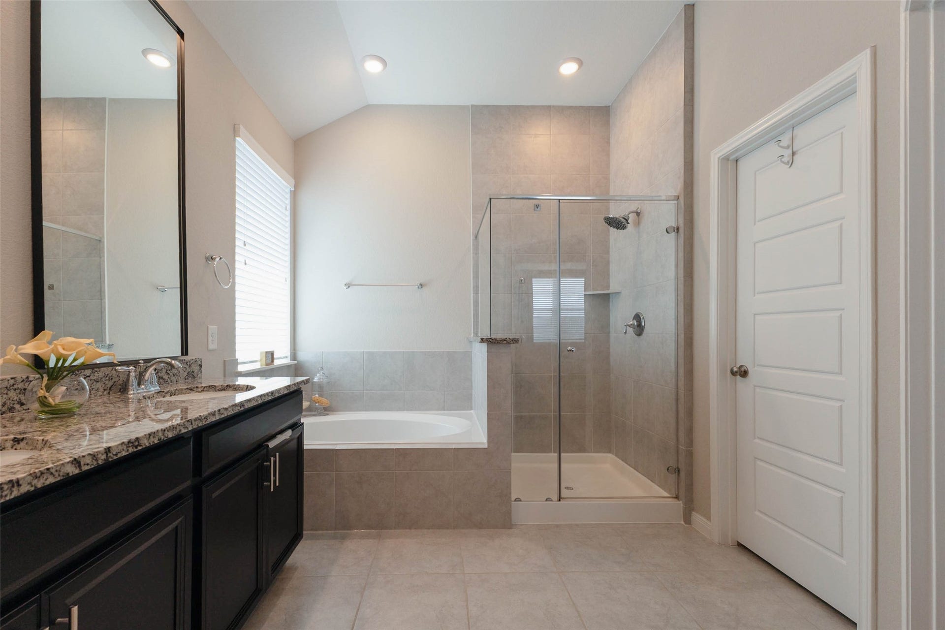 Additional primary bathroom view highlighting the glass-enclosed shower, soaking tub, and convenient access to the walk-in closet.
