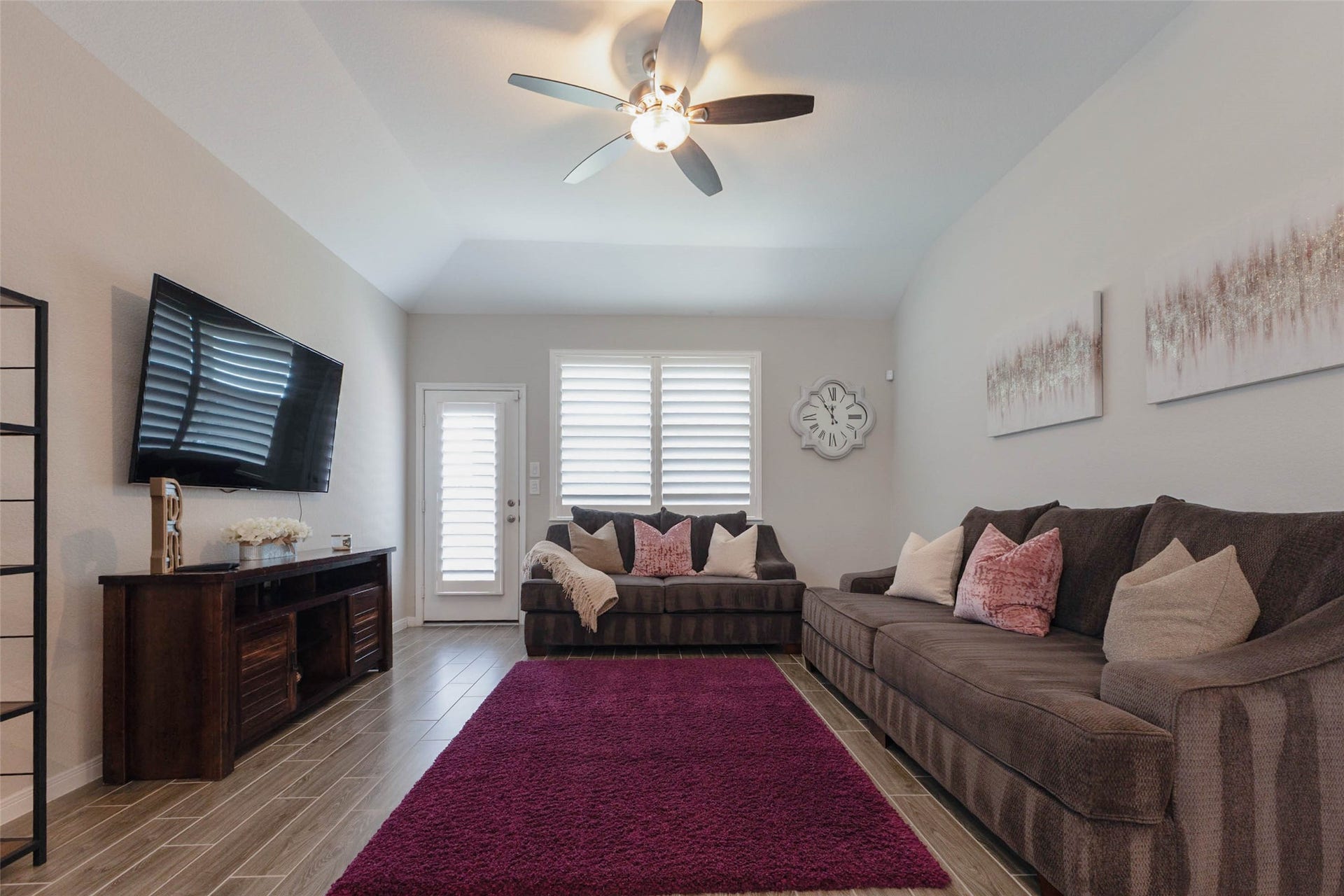 Inviting living room featuring a ceiling fan, abundant natural light, and comfortable space for relaxing or entertaining.