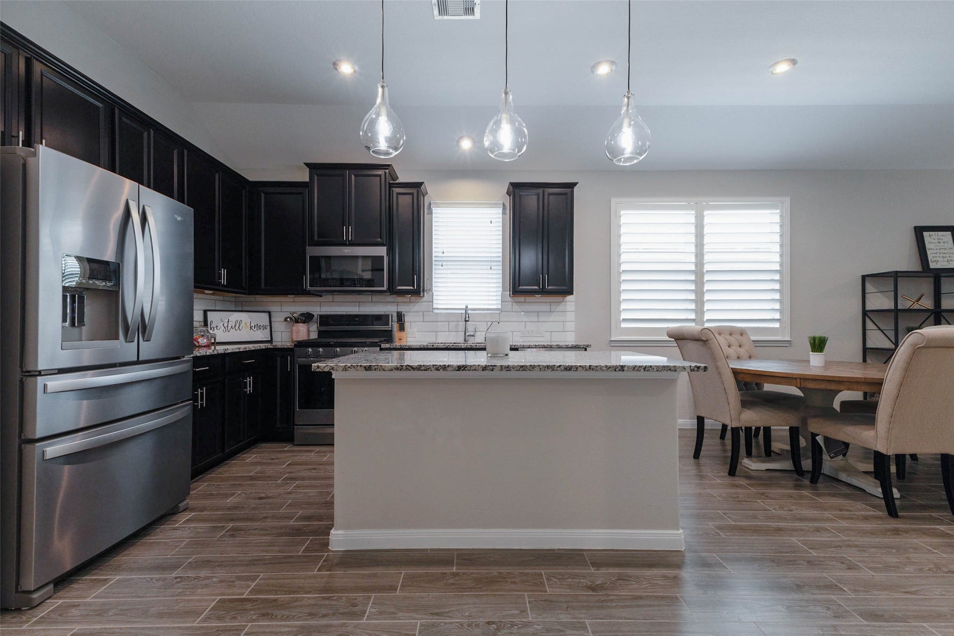 Beautiful kitchen showcasing dark cabinetry, stainless steel appliances, a generous island, and an adjoining dining area.
