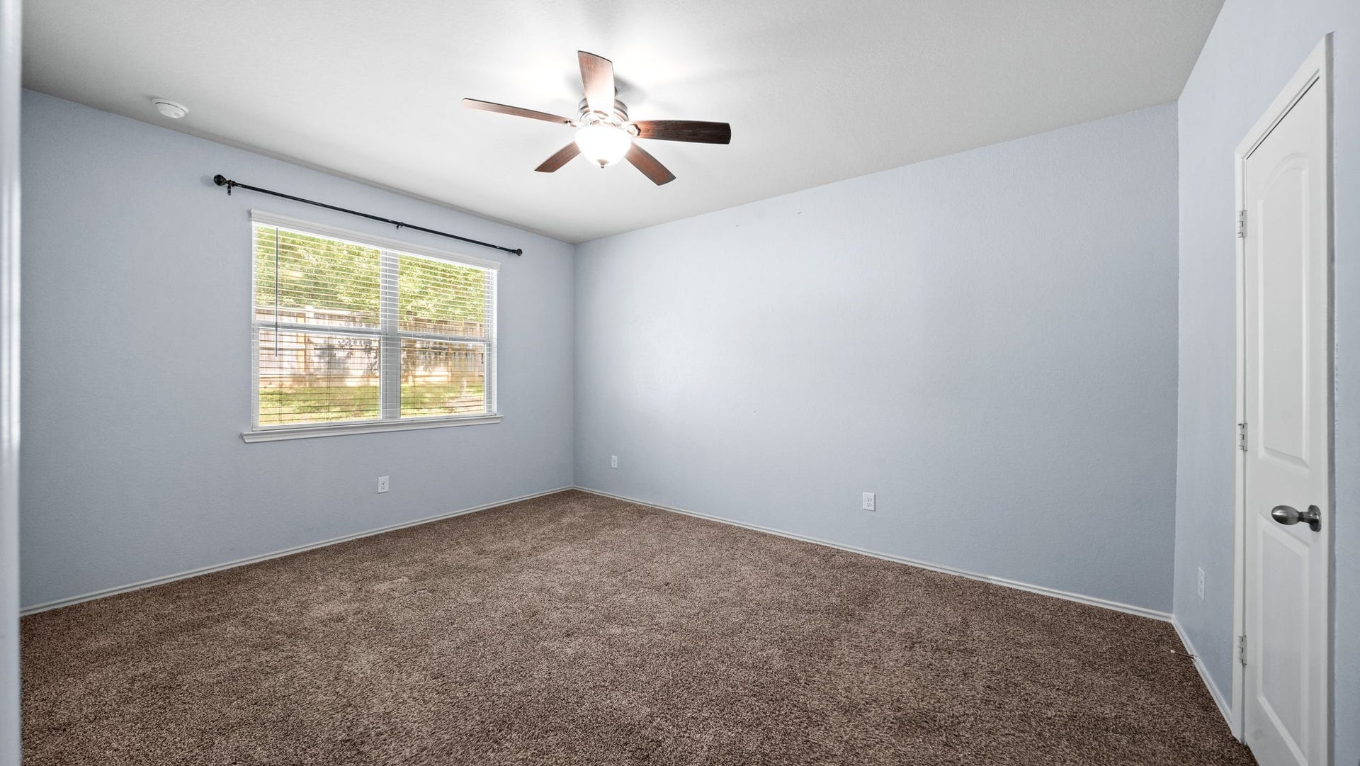 11502 Castle Nugent Court, Conroe, TX 77304 Spacious primary bedroom offers a peaceful retreat with a ceiling fan and relaxing views of the backyard.