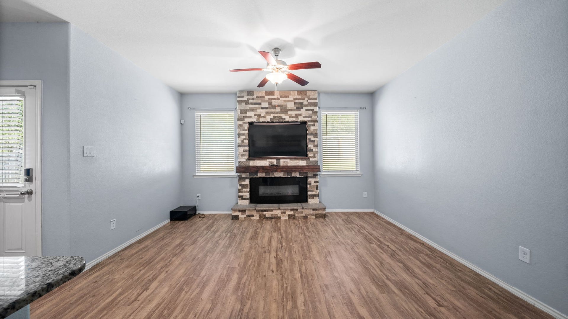 11502 Castle Nugent Court, Conroe, TX 77304 Relax and unwind in this comfortable living room featuring a stunning stone fireplace, ceiling fan, and easy-care vinyl plank flooring.
