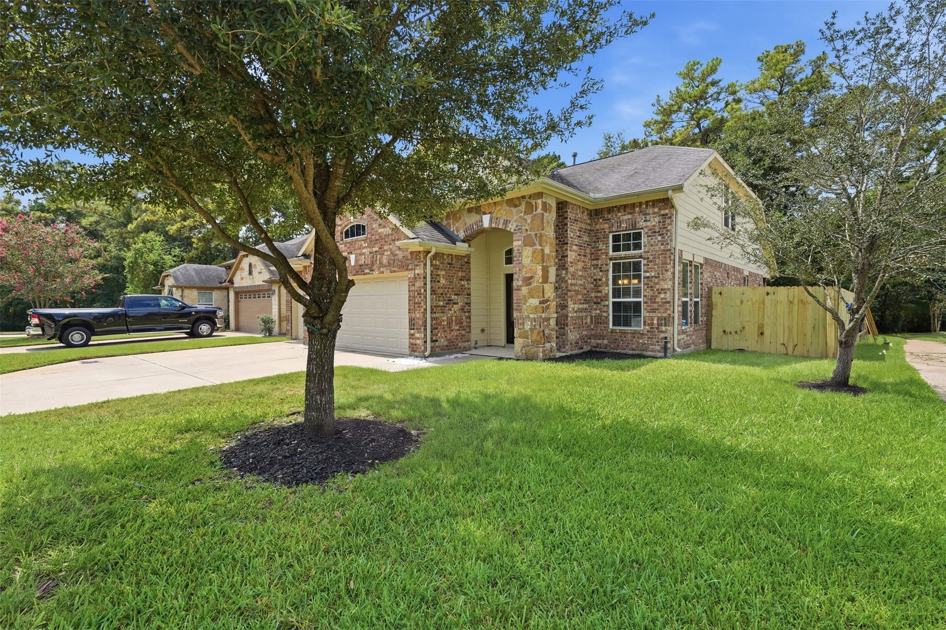 Classic brick and stone with an arched entry, a manicured lawn and mature shade trees. The side yard leads back to a fully fenced backyard.
