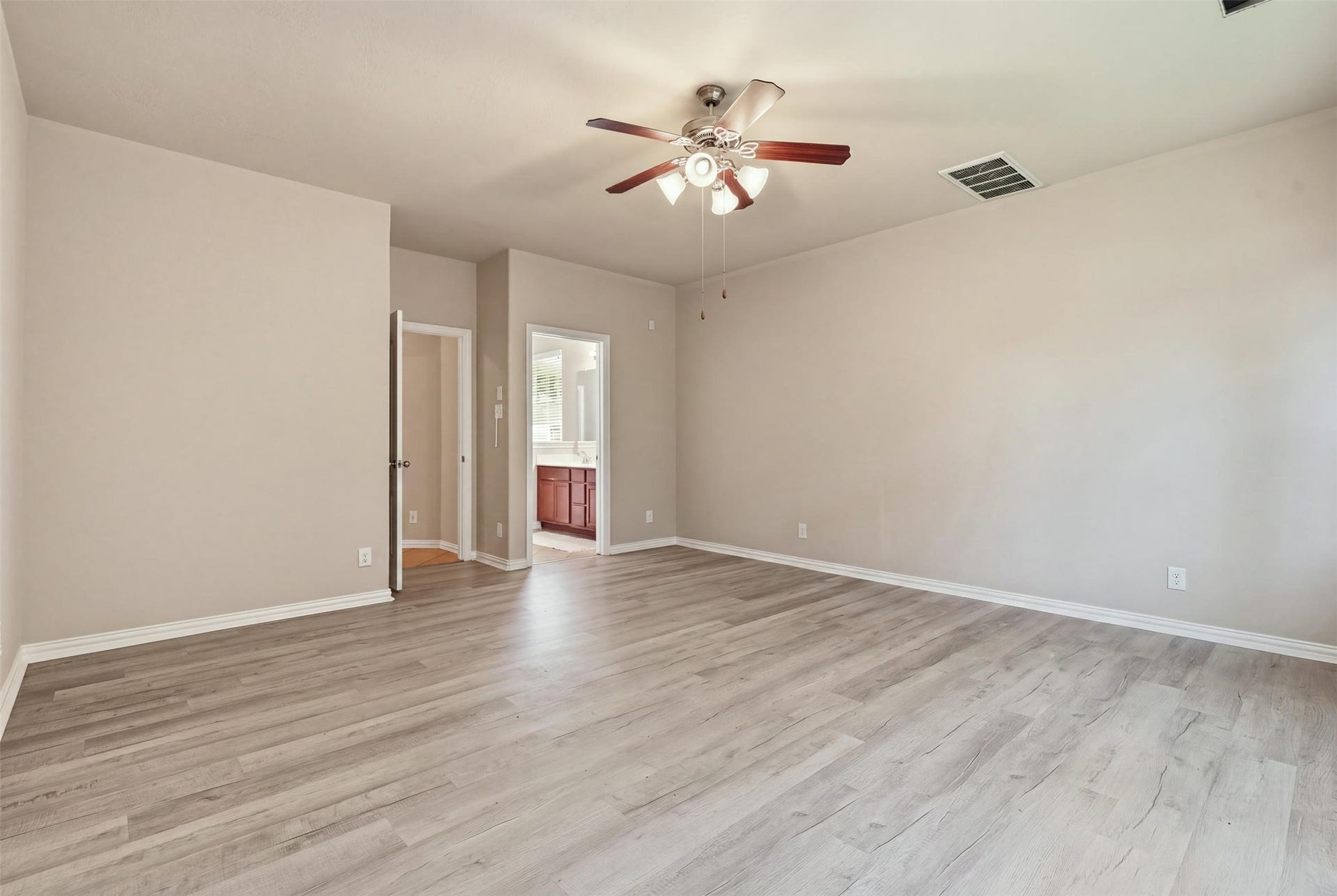 Everything within reach: the primary bedroom opens to its private bath and walk-in closet, with plenty of wall space for a king bed and a reading chair.