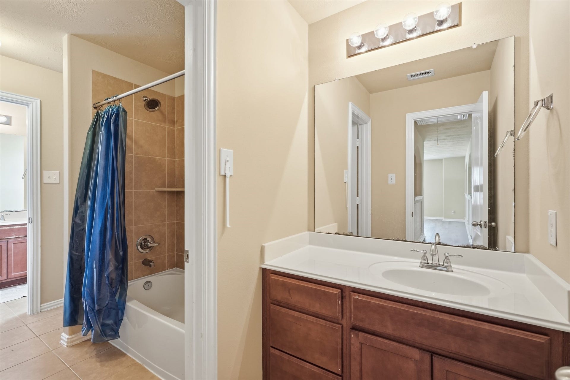 A secondary bath built for busy mornings: the vanity sits apart from the tub/shower room, with a tile surround and a large mirror.