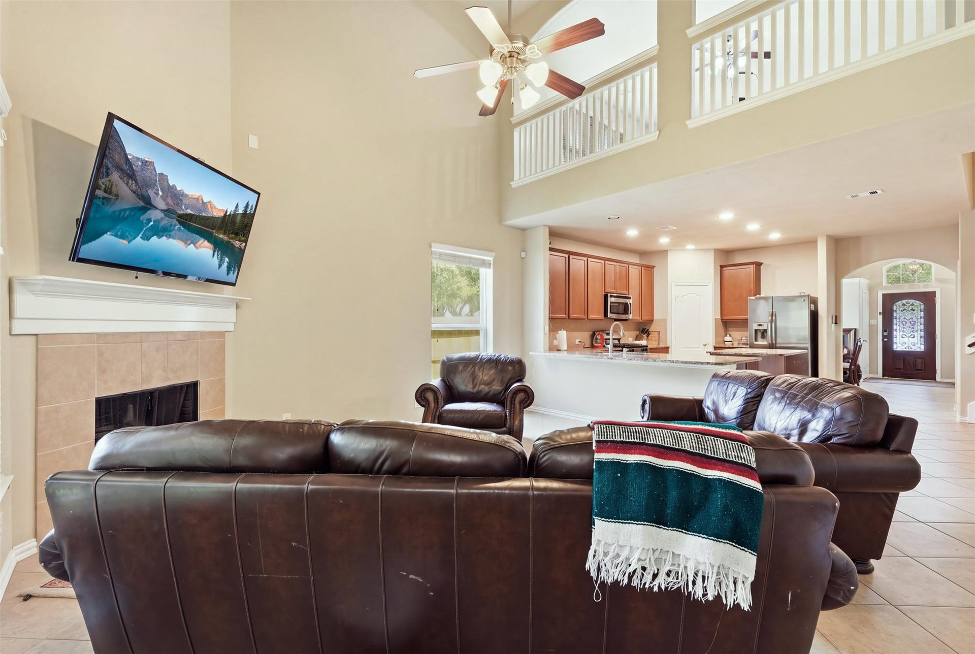 The open-concept payoff: the living room flows straight into the kitchen, with the upstairs overlook above and sight lines all the way to the front door. Hosting just got easy.
