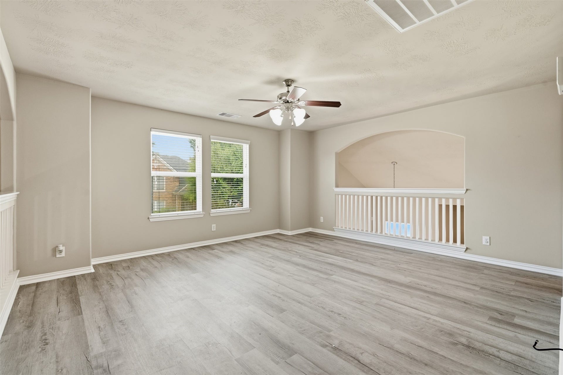 The upstairs game room (loft) has an arched overlook to the living room below, a ceiling fan and wood-look plank floors. Movie nights, a gaming setup or a home gym: you pick.