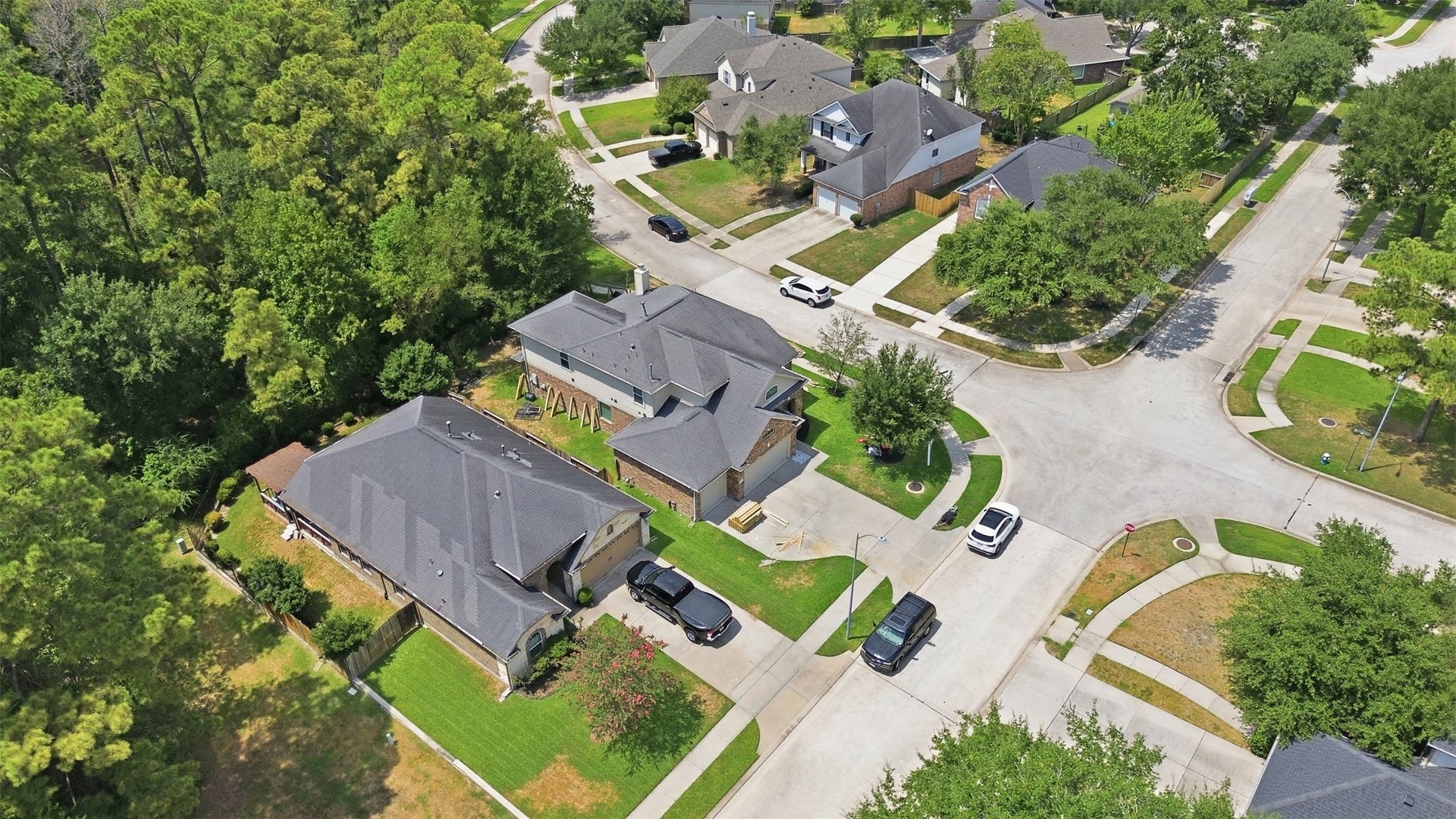 Spring Trails from the air: tree-lined streets, sidewalks and wooded green space, with the home tucked beside a natural buffer of trees.