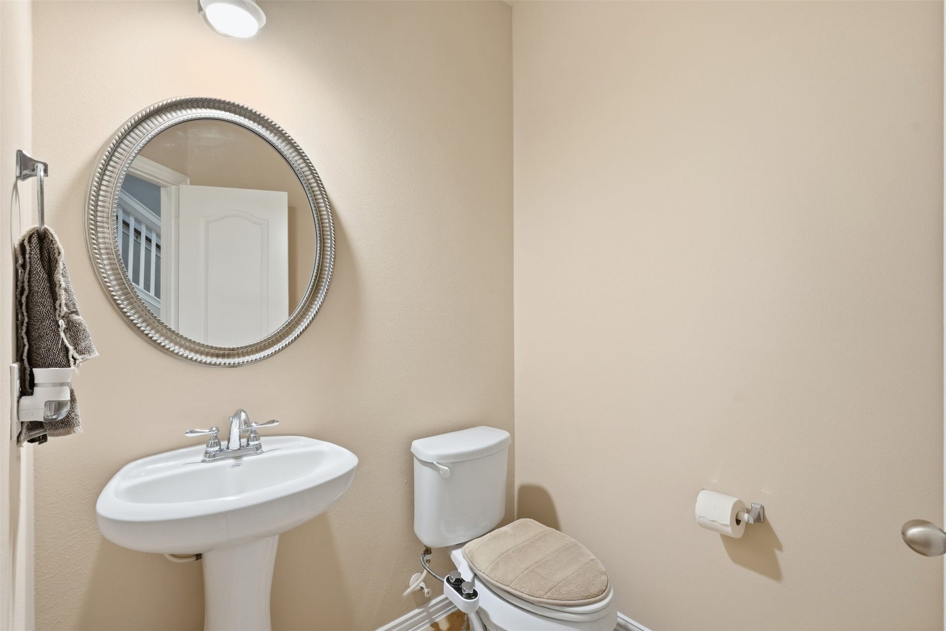 Guest-ready half bath on the main floor, with a pedestal sink and warm neutral walls.