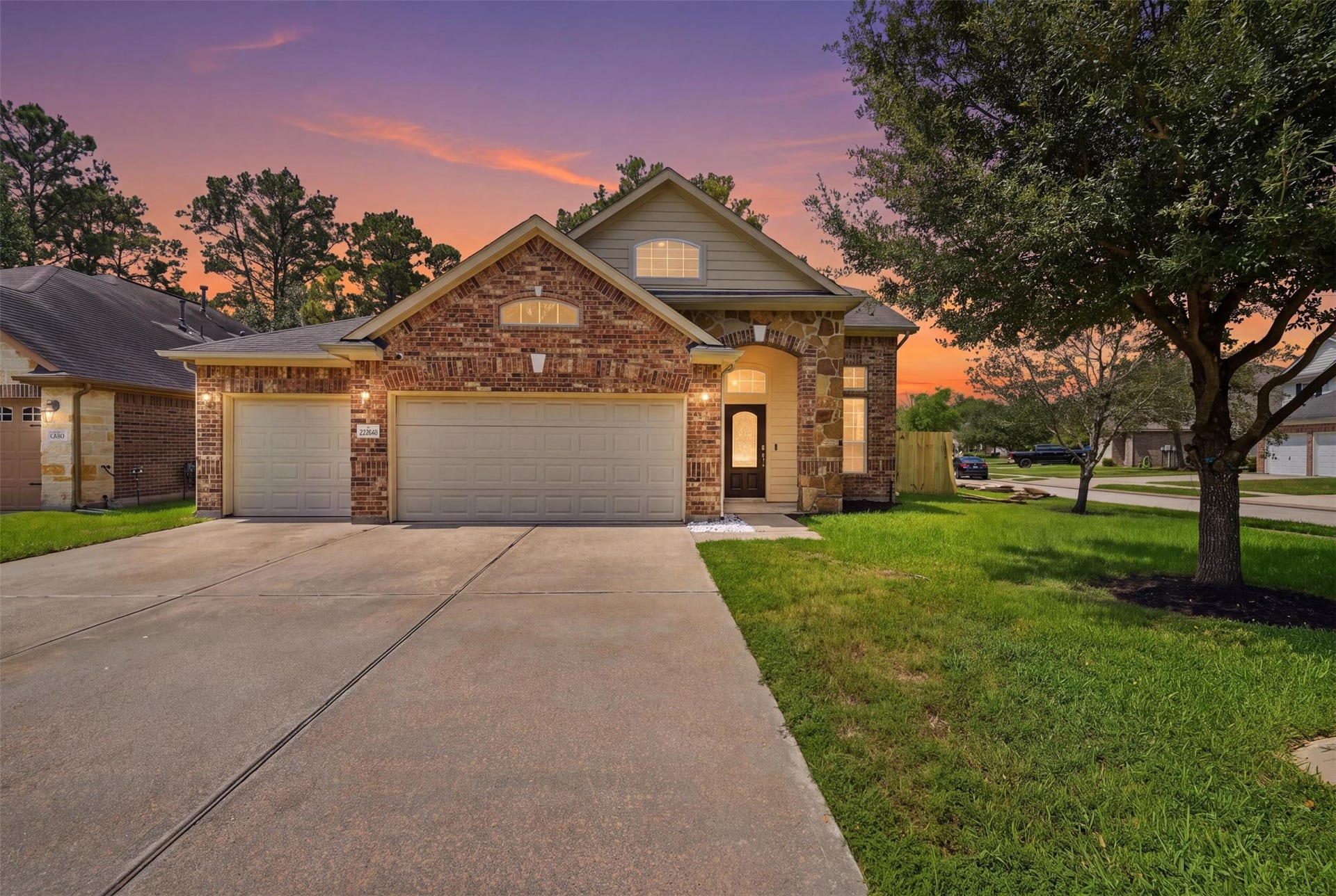 Golden-hour glow on the same brick-and-stone facade: warm porch lights, arched windows and a front walk that says welcome home. Virtual twilight enhancement; sky and lighting digitally edited.