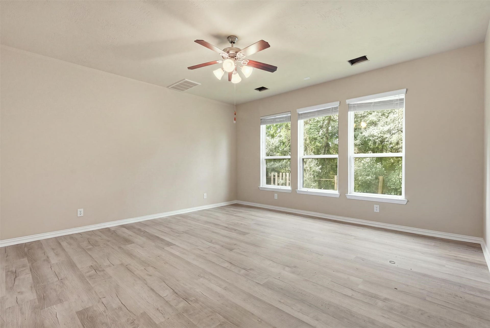 Morning light and treetop views. Triple windows in the primary suite bring the outdoors in, and the wood-look plank flooring keeps it clean and modern.