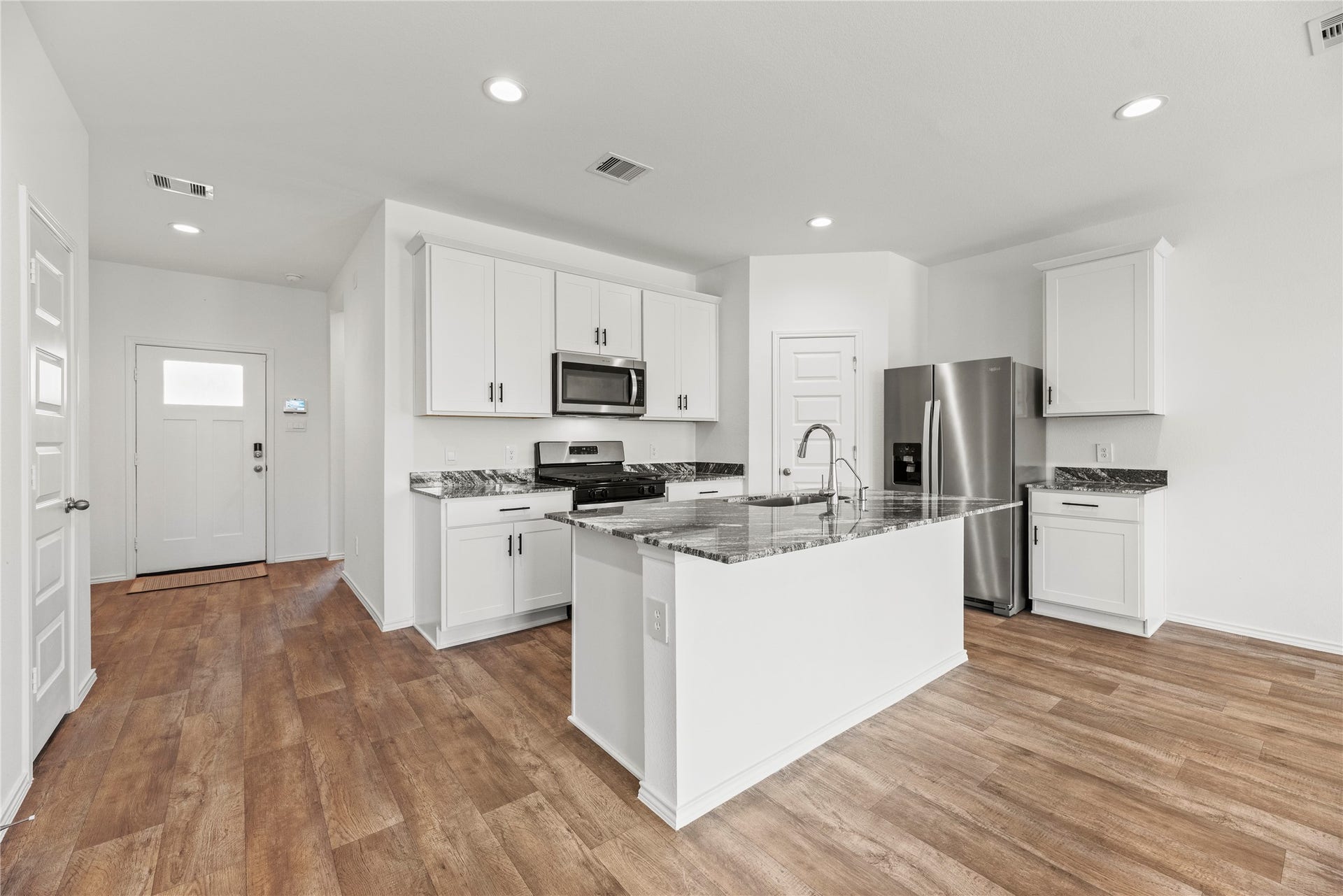 2815 Magnolia Blossom Lane, Rosenberg, TX 77469 The heart of the home is this kitchen featuring premium quartz countertops, white cabinetry and a large central island with breakfast bar, perfect for food prep or casual dining.