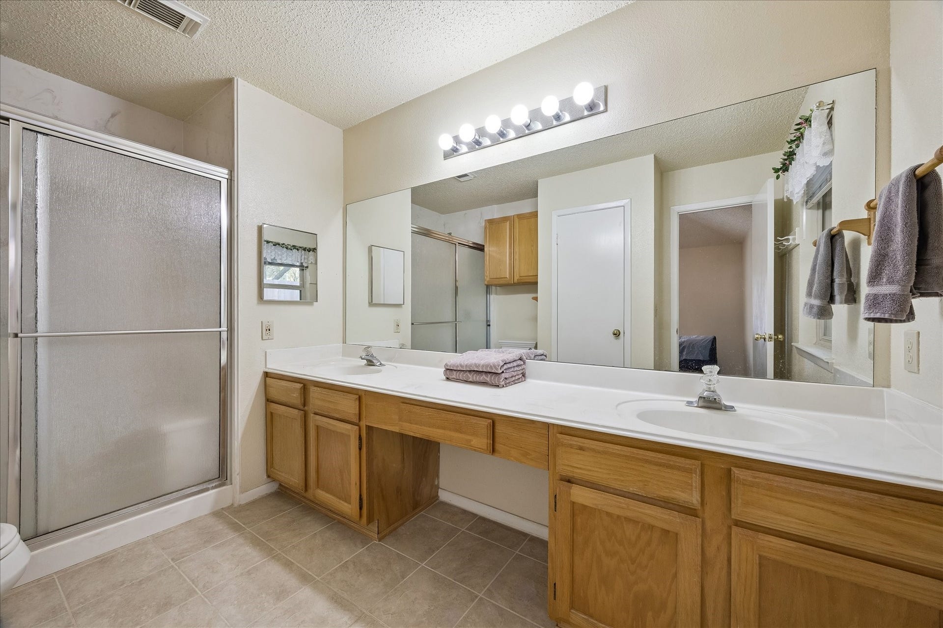 Ensuite bath with two vanities and Hollywood style lighting.