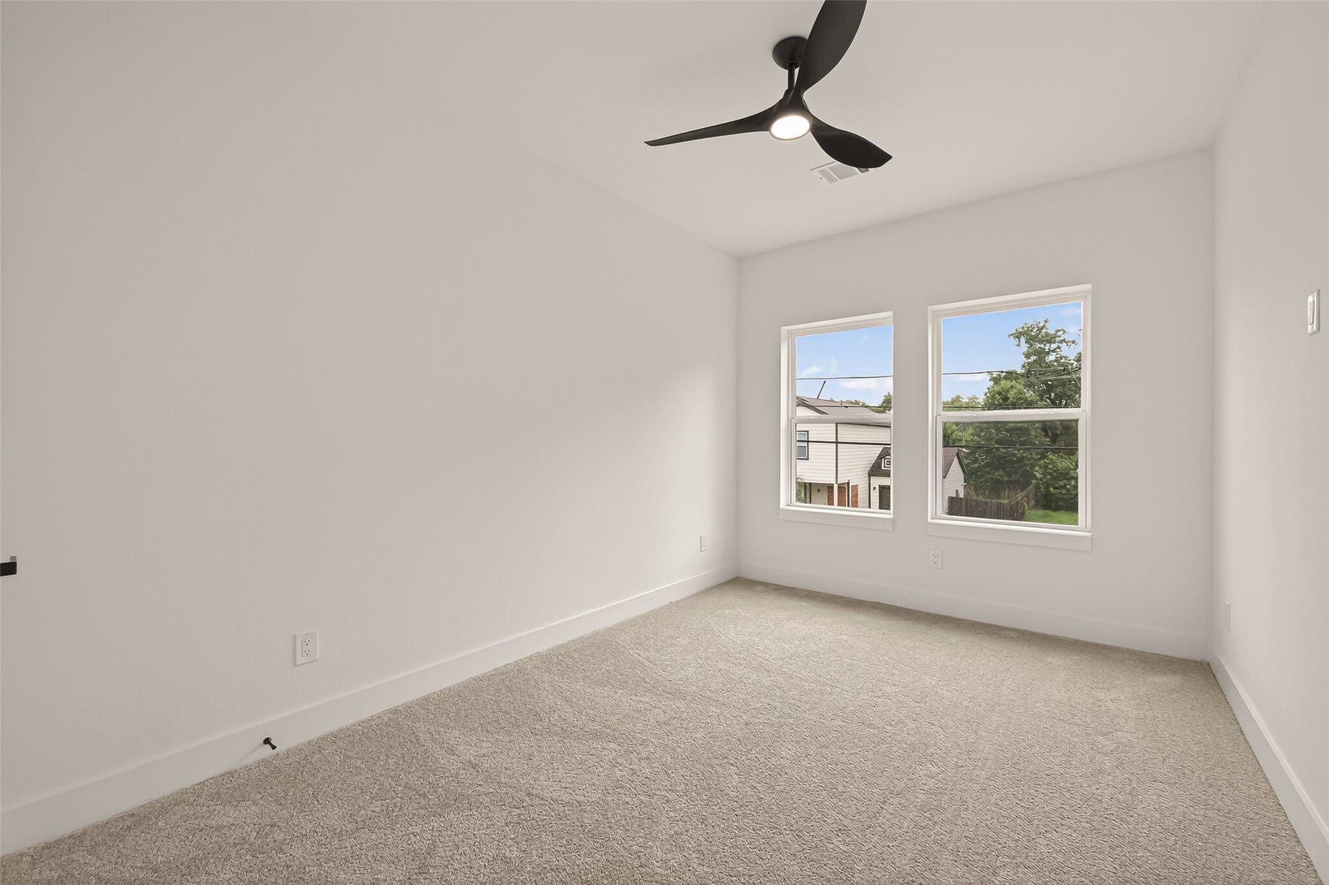 6808 Madrid Street, Houston, TX 77021 This bright bedroom features neutral carpeting, fresh white walls, and two large windows that offer ample natural light. A modern ceiling fan adds a stylish touch.