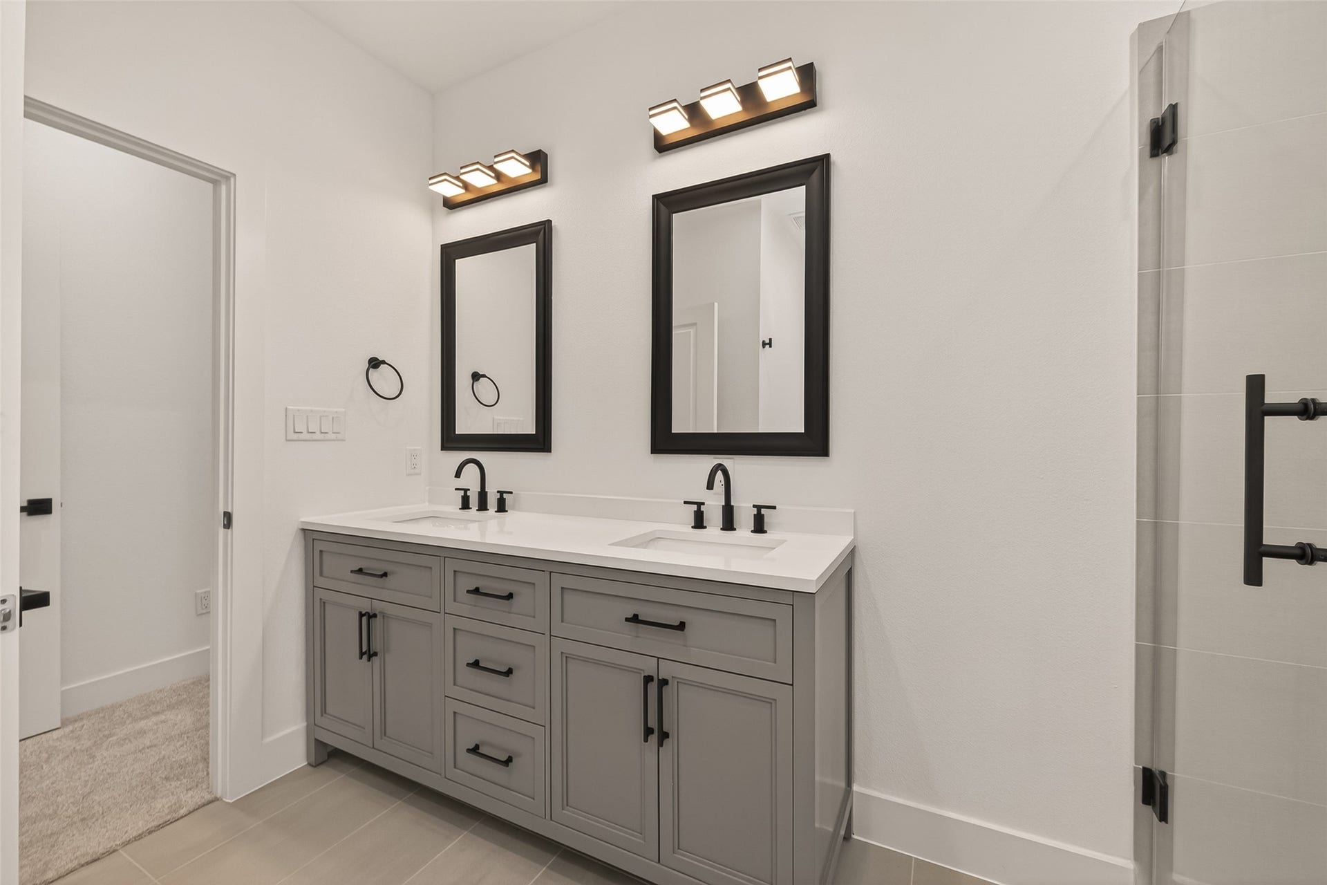 6808 Madrid Street, Houston, TX 77021 This bathroom features a modern double vanity with sleek black fixtures, framed mirrors, and ample storage. The neutral tones and contemporary lighting create a bright, clean, and stylish atmosphere.