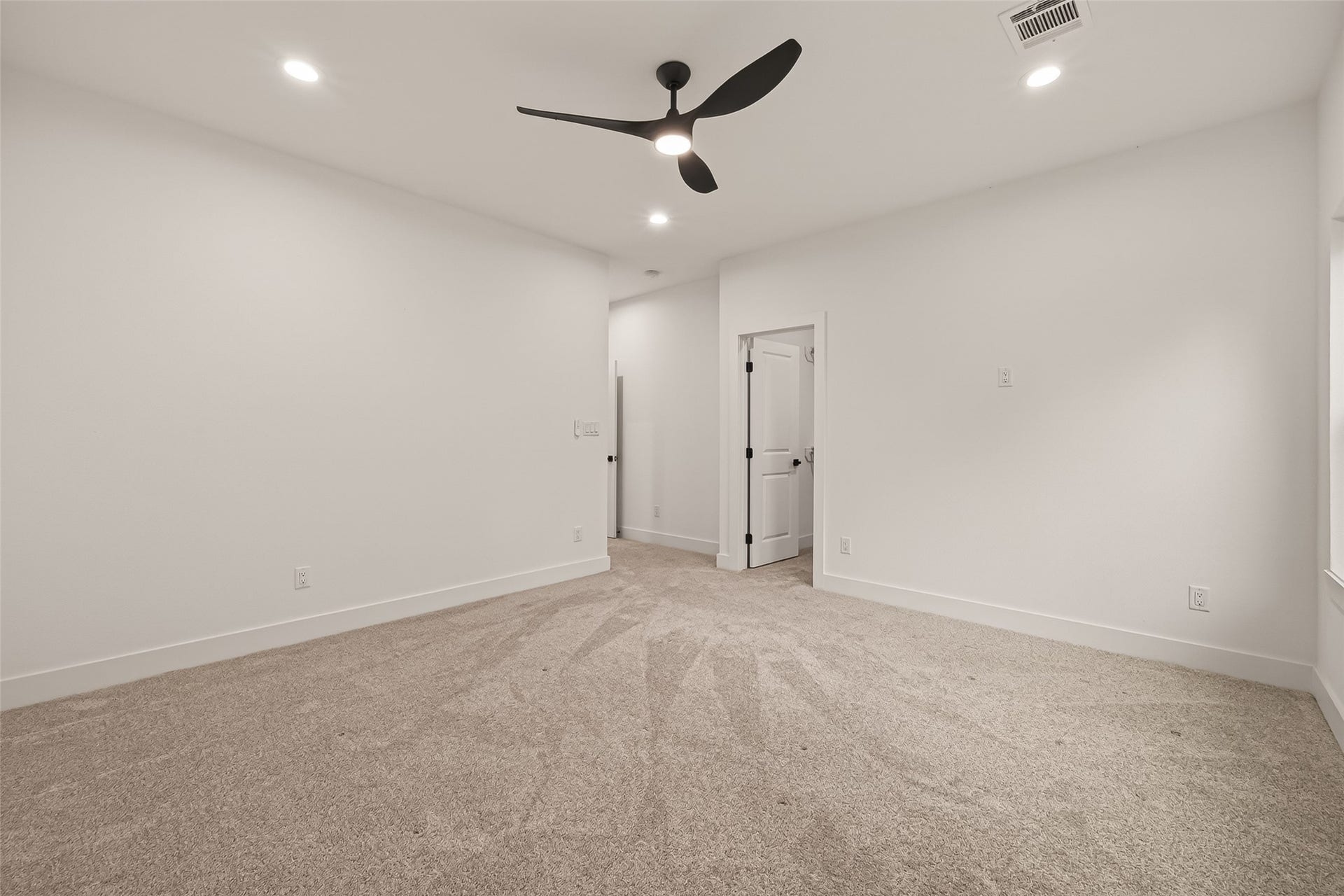 6808 Madrid Street, Houston, TX 77021 This room features plush carpeting, white walls, recessed lighting, and a modern ceiling fan. It has a clean, spacious feel with a door leading to another area, ideal for a bedroom or office.
