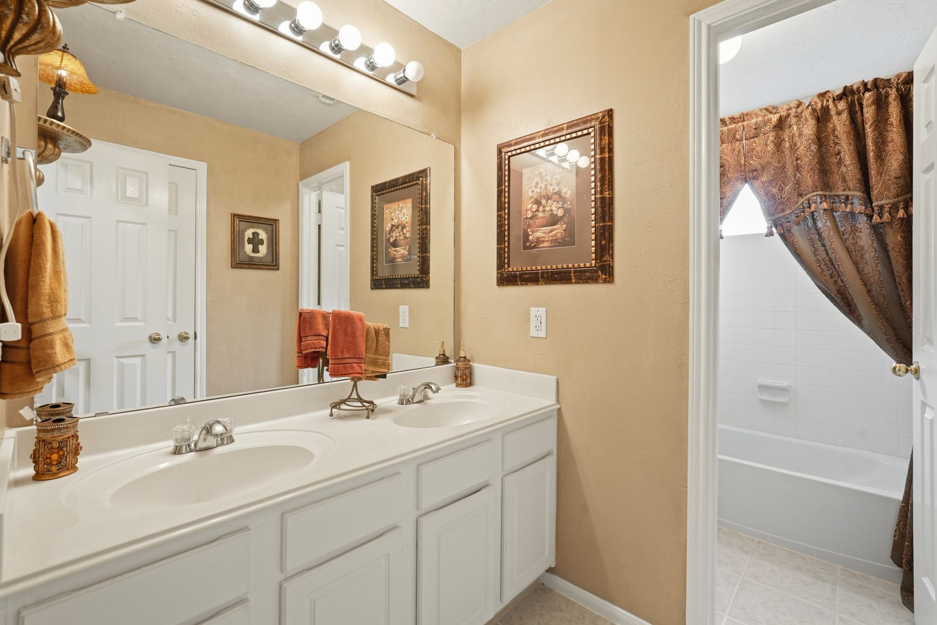 This large secondary bath features dual sinks, tile surround tub/shower and tile floors.