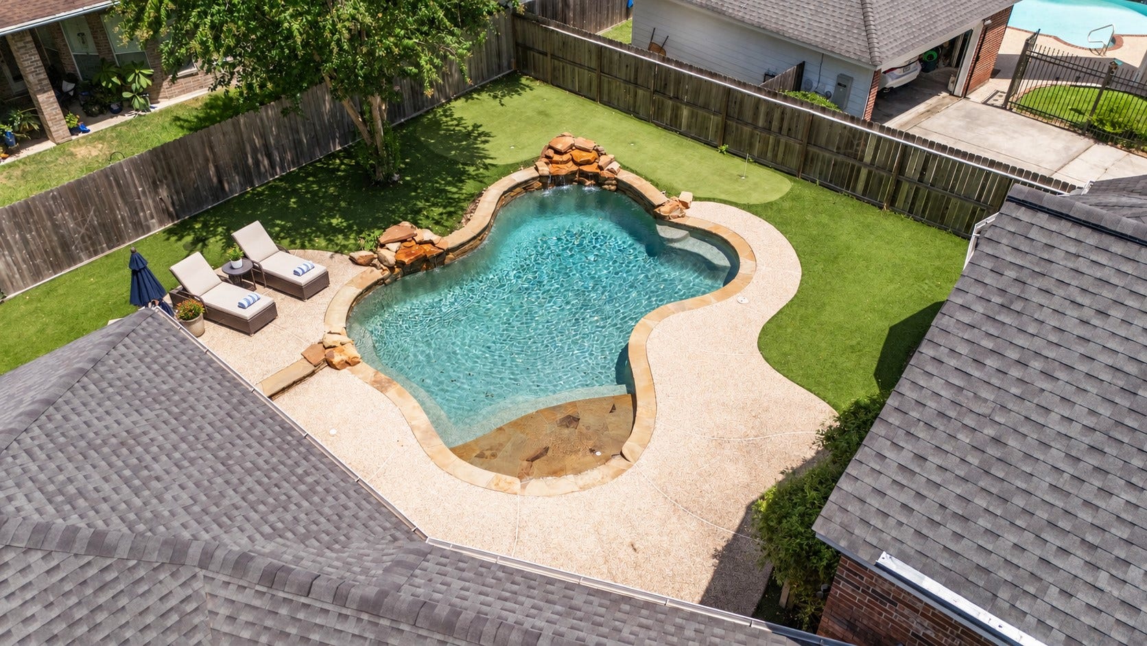 Aerial view showcases the PRIVATE BEACH-ENTRY POOL, surrounding patio and low-maintenance backyard. Outdoor furniture virtually staged.