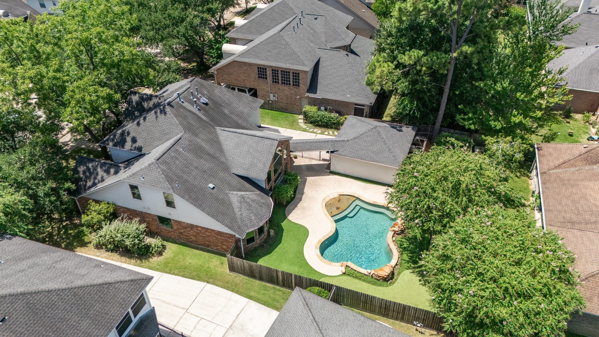 Aerial view showcases the home, detached garage, PRIVATE POOL and low-maintenance backyard turf.