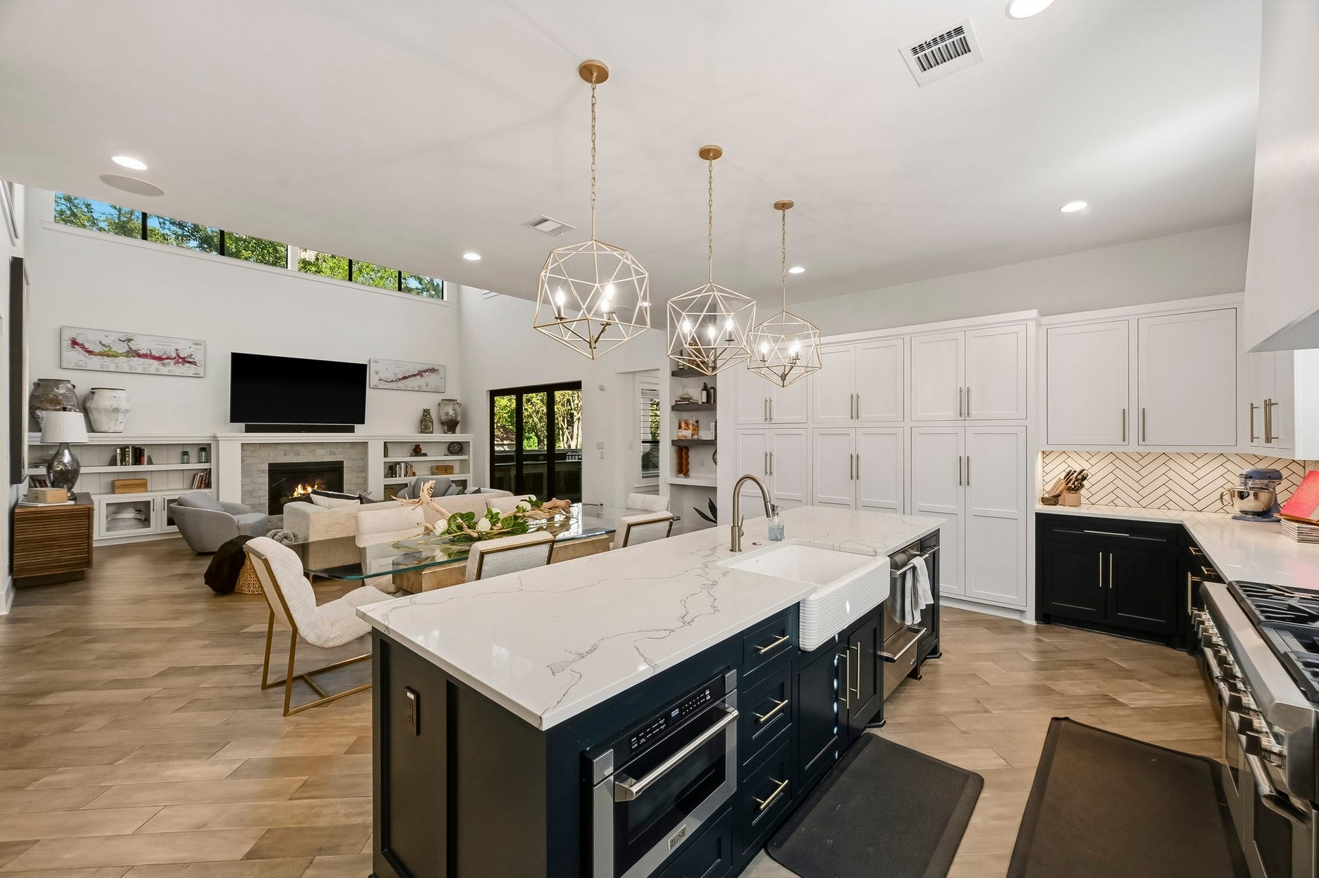 Island kitchen complete with designer finishes, herringbone pattern tile backspalsh and farmhouse sink.