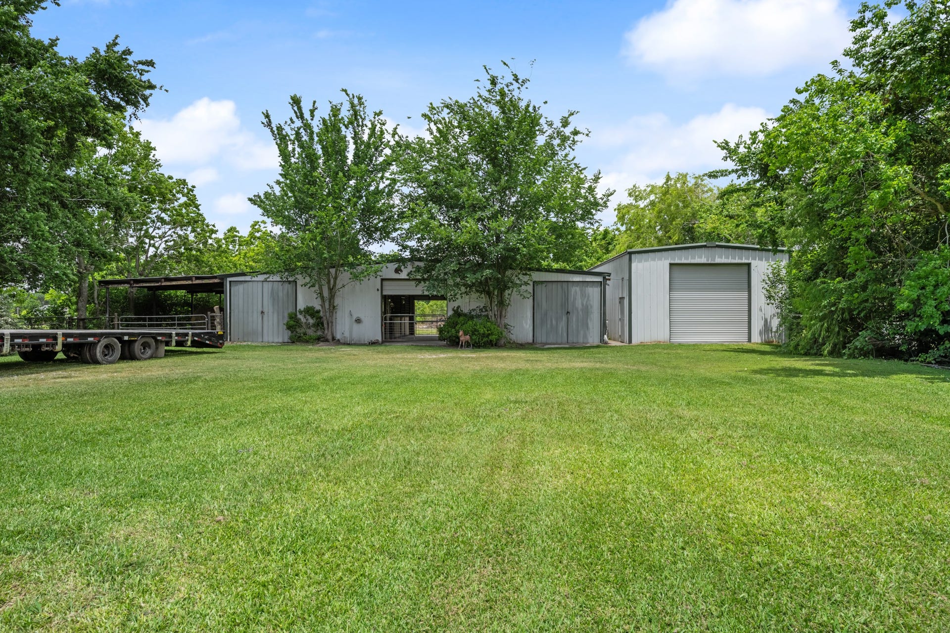 15602 Fir Road, Santa Fe, TX 77517 Versatile outbuildings include a horse barn and an insulated workshop, offering ample space for livestock, equipment storage, hobbies, or business use. Surrounded by mature trees and open green space, this setup is ideal for country living and recreational use.