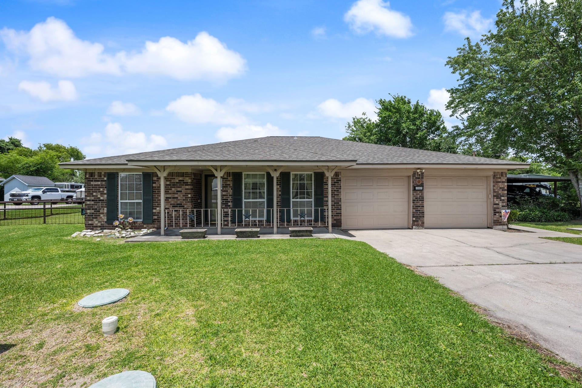 15602 Fir Road, Santa Fe, TX 77517 Charming single-story brick home featuring a welcoming covered front porch, mature shade trees, and an expansive front lawn. The attached two-car garage and additional covered parking provide added convenience and functionality.