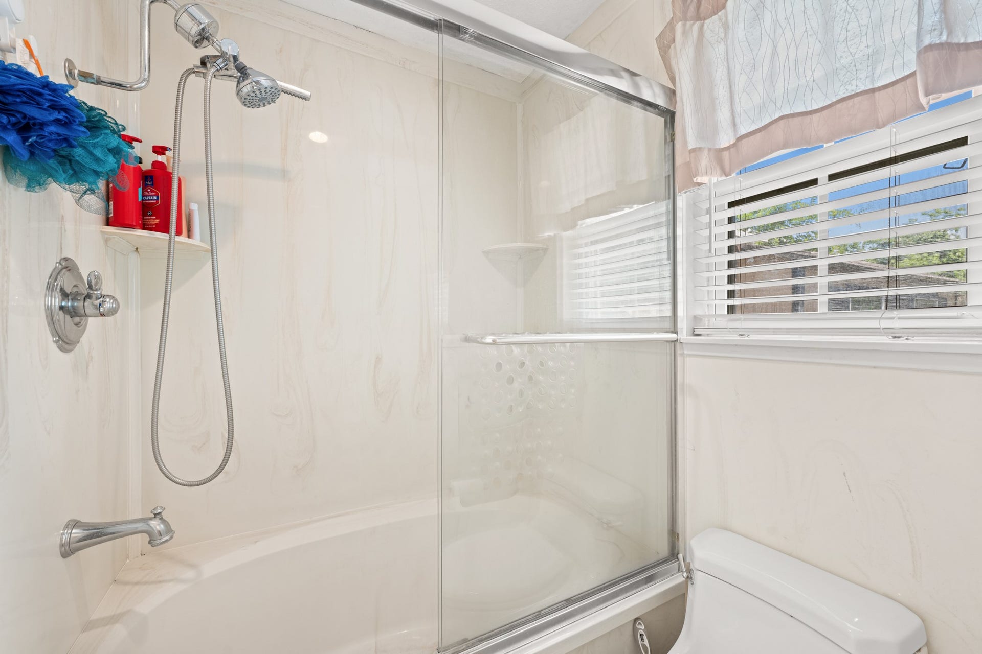15602 Fir Road, Santa Fe, TX 77517 Bright primary bathroom featuring a tub/shower combination with glass enclosure and natural light from the nearby window. Clean finishes and a functional layout create a comfortable and practical everyday space.