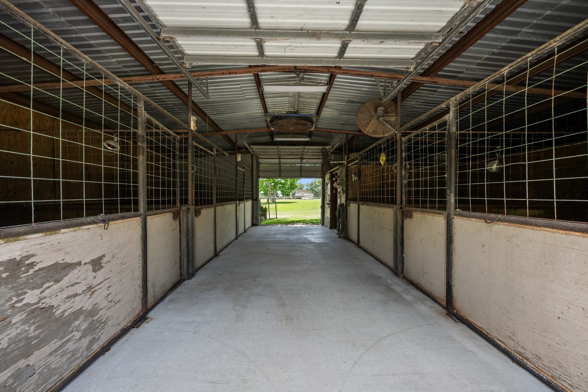 15602 Fir Road, Santa Fe, TX 77517 Spacious horse barn featuring multiple enclosed stalls, durable concrete flooring, overhead ventilation, and a wide center aisle for easy access and daily operation. Ideal setup for livestock care and equestrian use.
