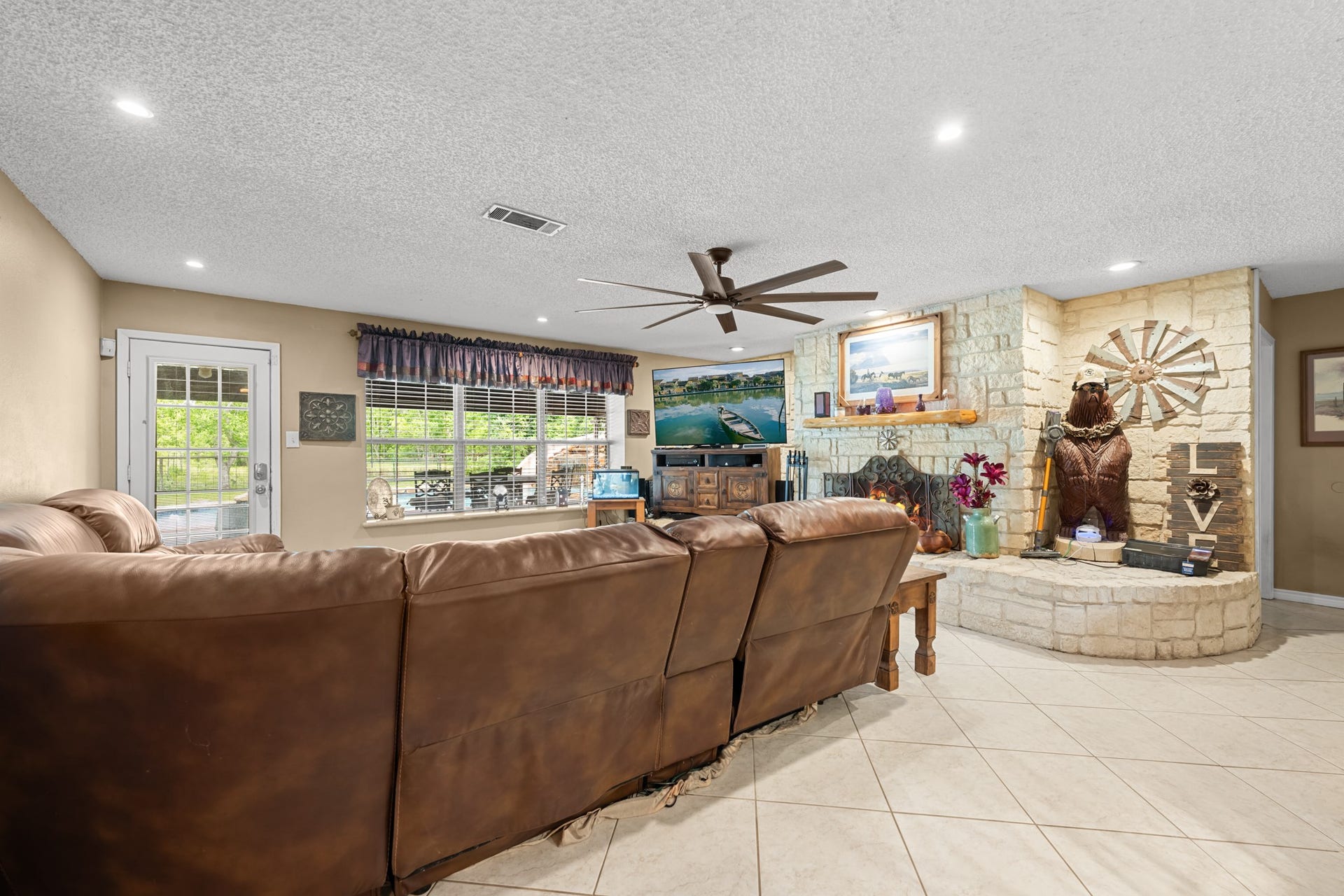 15602 Fir Road, Santa Fe, TX 77517 Expansive living area featuring a striking stone fireplace, recessed lighting, and oversized windows that fill the space with natural light. The open layout and generous seating area make this room ideal for relaxing or entertaining guests.