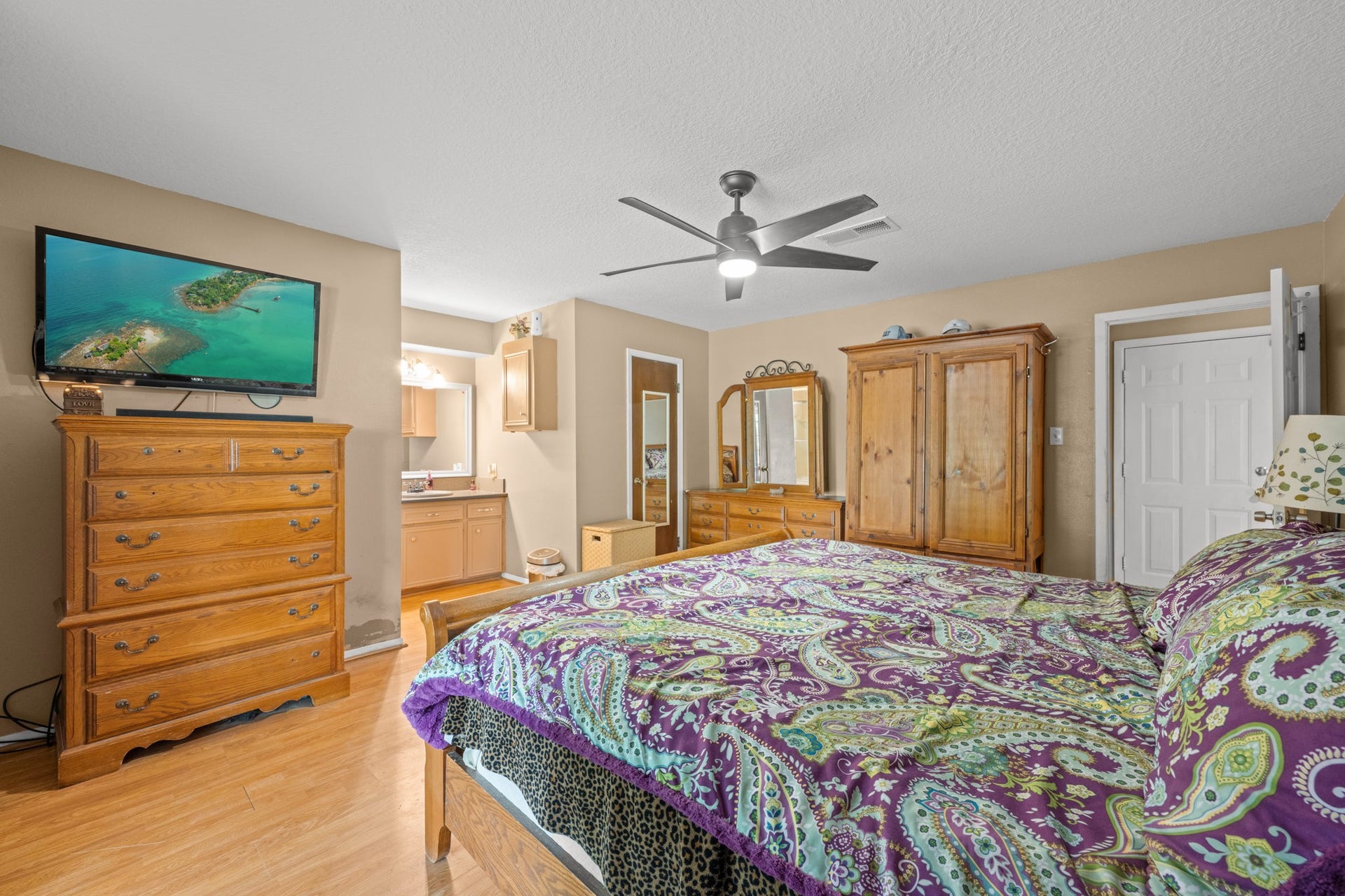 15602 Fir Road, Santa Fe, TX 77517 Generously sized primary suite featuring wood-look flooring, modern ceiling fan, and a spacious layout with room for additional furnishings. The ensuite vanity area and abundant storage enhance both comfort and everyday functionality.