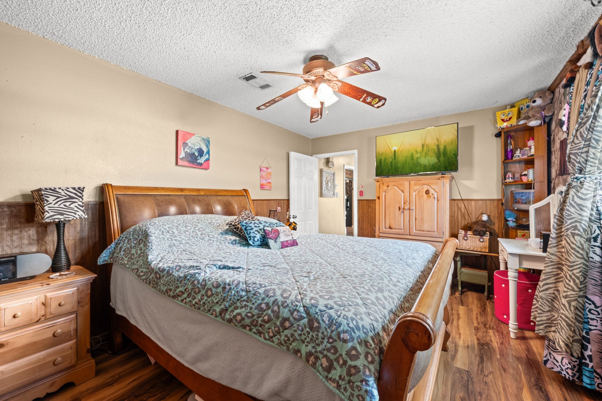 15602 Fir Road, Santa Fe, TX 77517 Generously sized secondary bedroom with wood-look flooring, ceiling fan, and ample space for larger furnishings. Large windows and warm finishes create a bright and comfortable retreat with flexible use options.