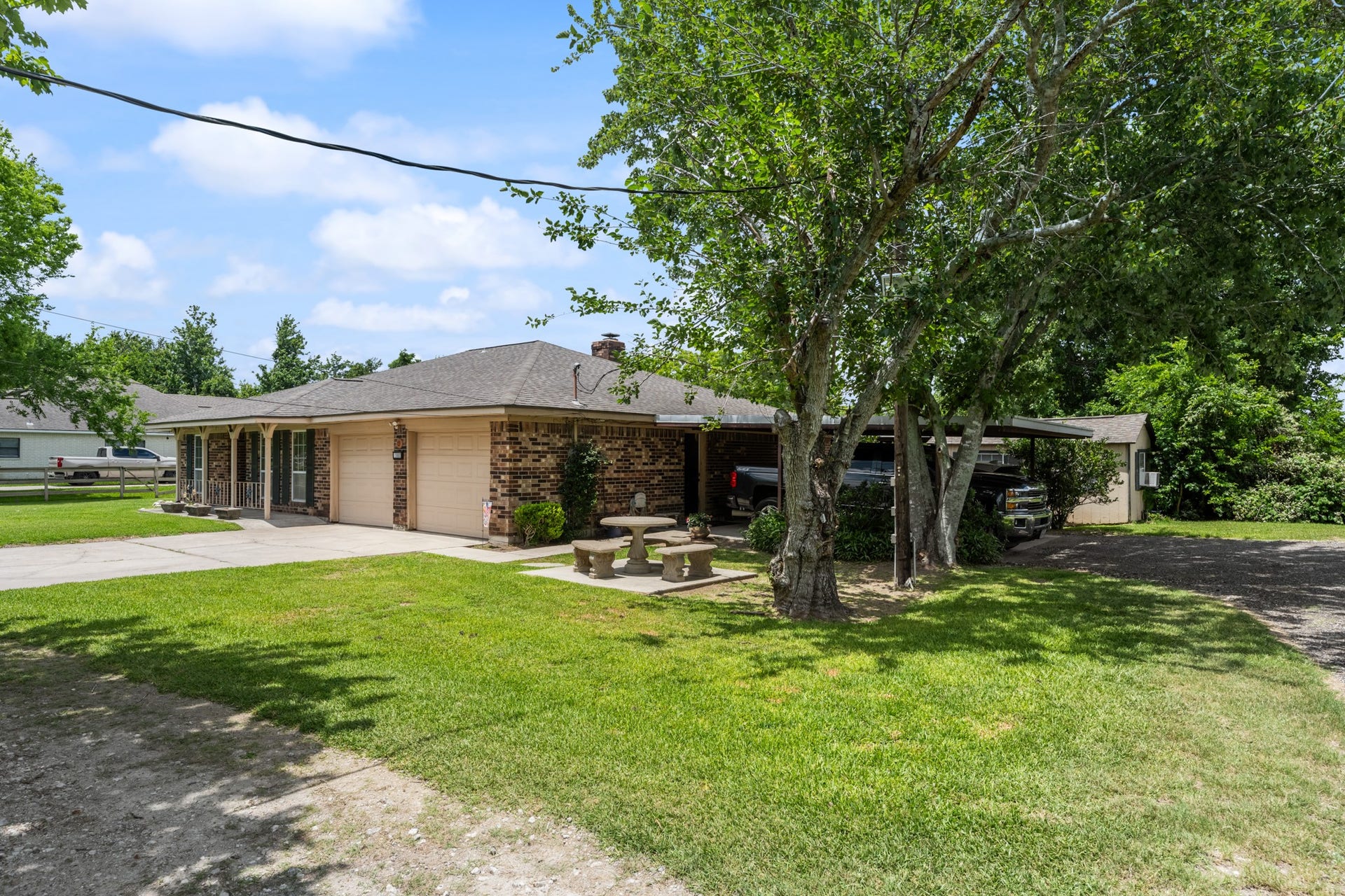 15602 Fir Road, Santa Fe, TX 77517 Charming brick exterior with mature shade trees, a spacious driveway, attached garage, and covered parking for added convenience. The expansive front lawn and country-style setting create a welcoming first impression.