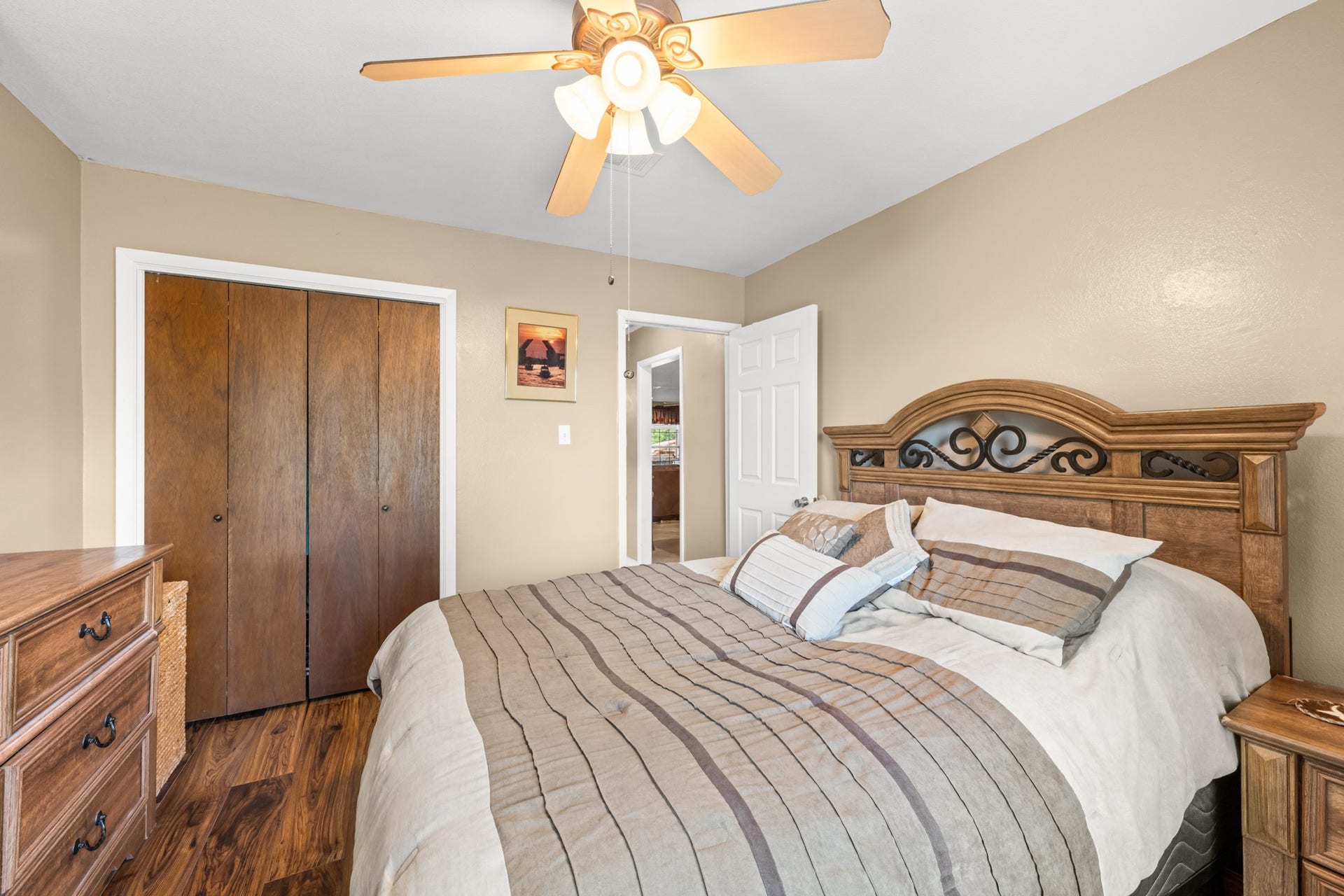 15602 Fir Road, Santa Fe, TX 77517 Spacious bedroom with rich wood-look flooring, neutral color palette, and ample closet storage. The ceiling fan and well-designed layout provide a comfortable and relaxing space to unwind.
