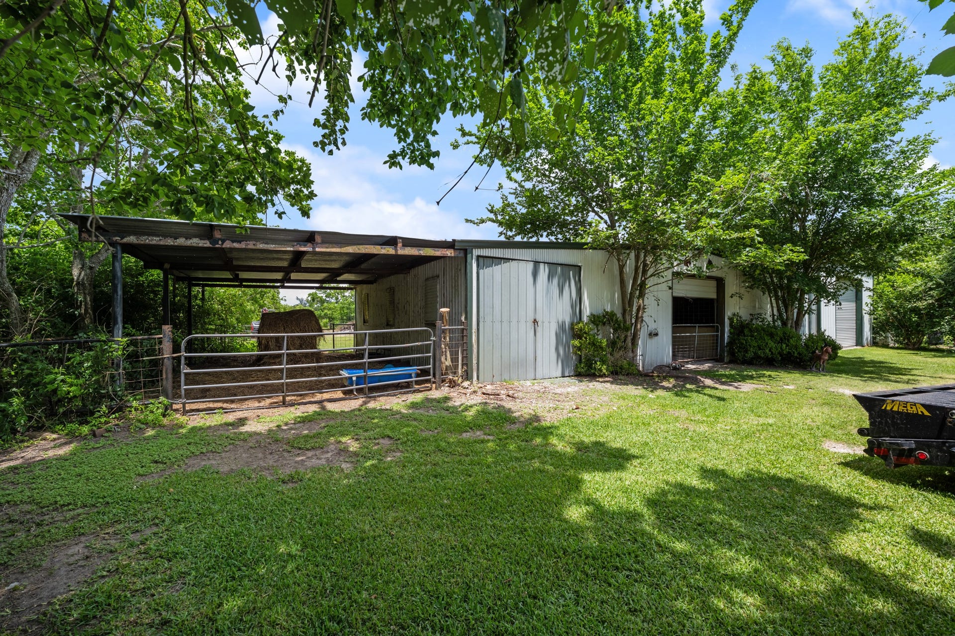 15602 Fir Road, Santa Fe, TX 77517 Functional horse barn with covered stalls and fenced areas, offering excellent space for livestock care, feed storage, and everyday operations. Surrounded by mature trees and open green space for a peaceful country setting.